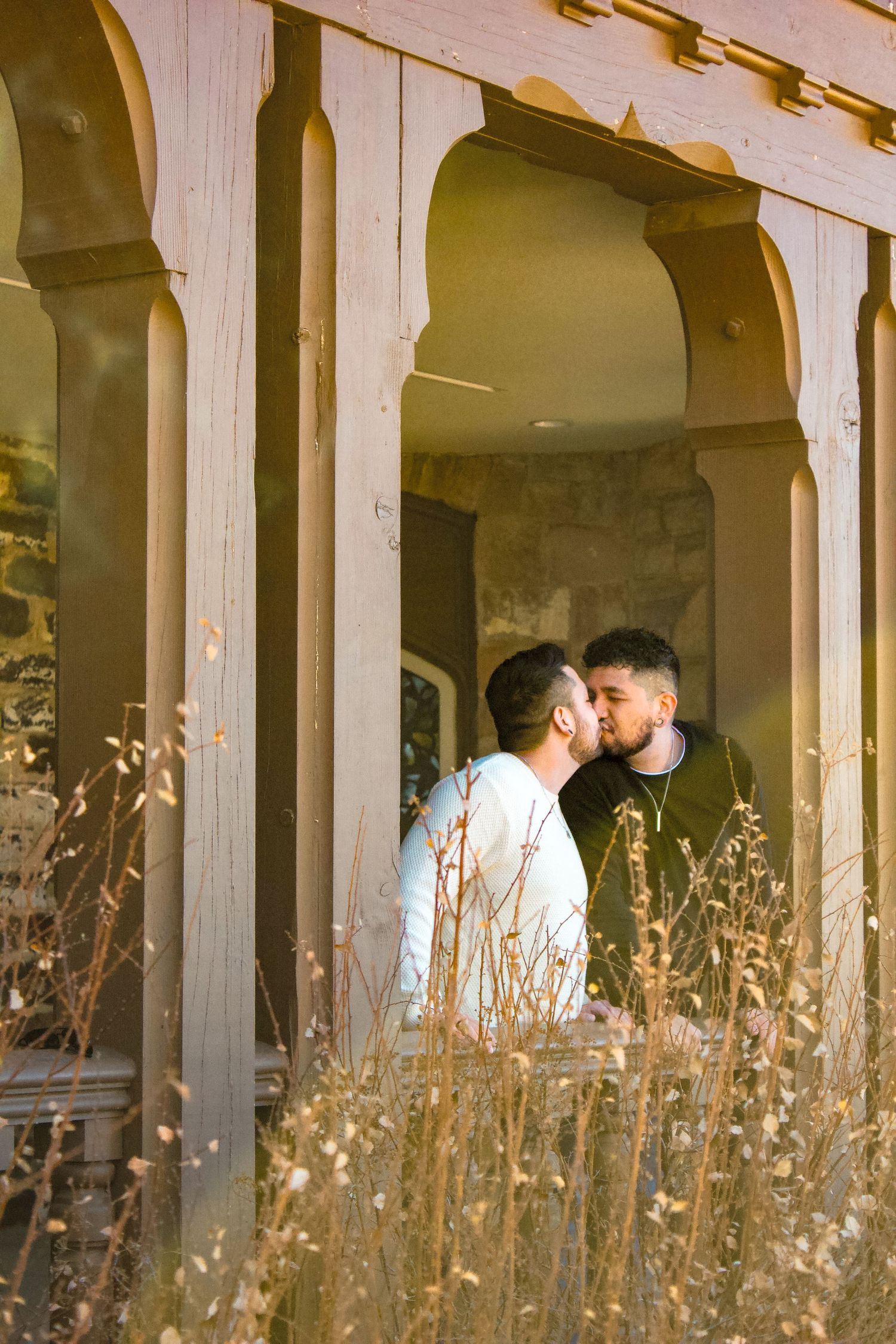 Intimate moment captured through stone archways with golden dried grass in natural lighting.