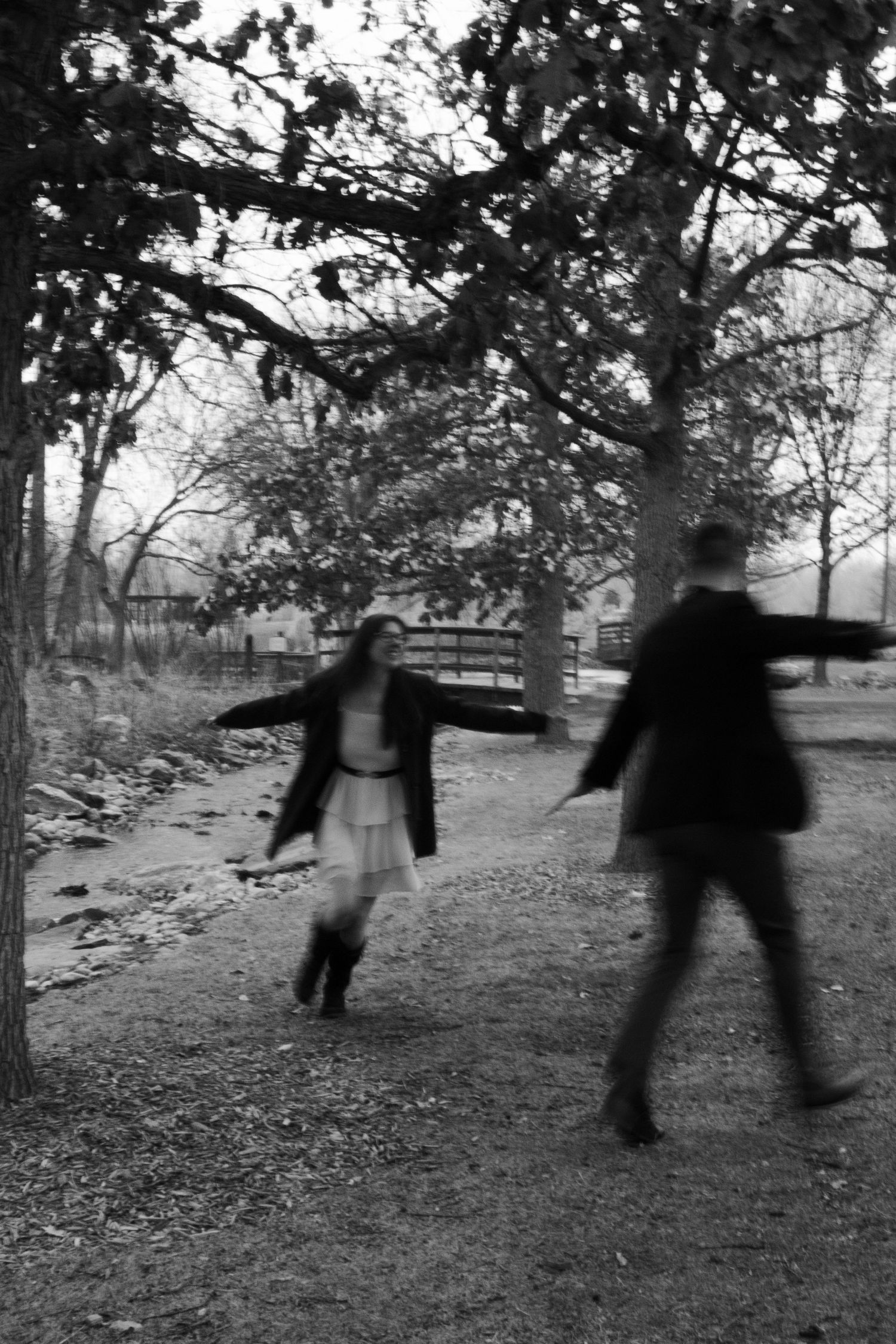 Two people dancing in a black and white photo on a leaf-covered path.