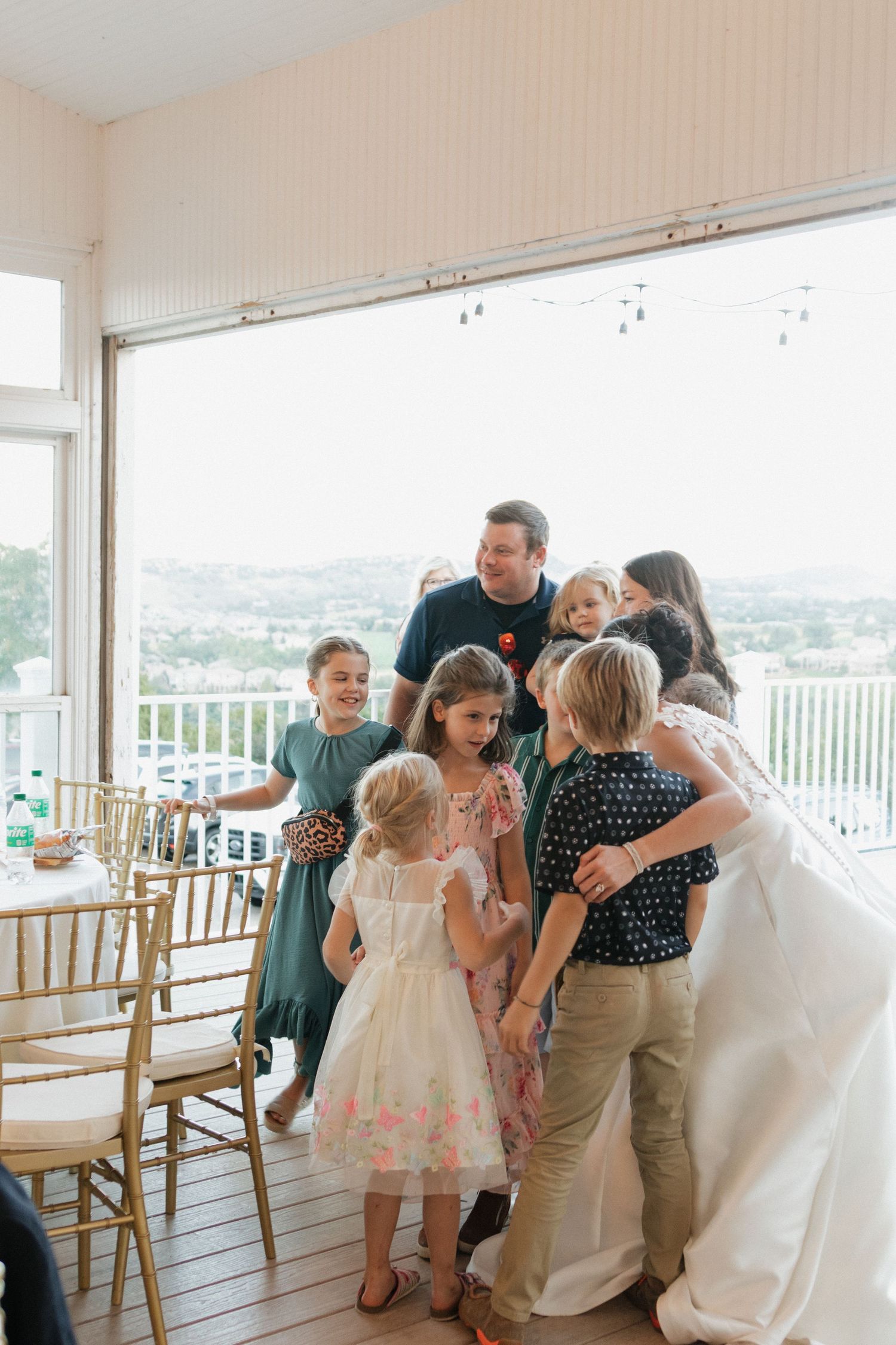Wedding guests and children gather in a bright reception room with panoramic views.