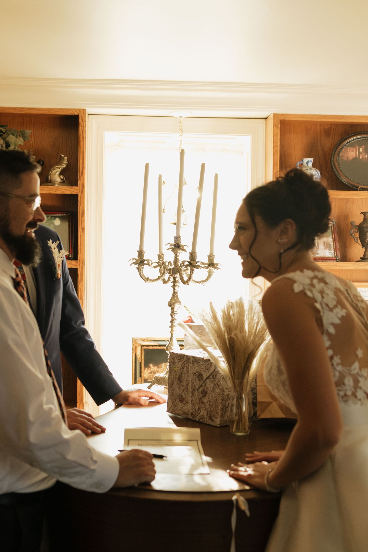 Wedding preparations in sunlit room with candlesticks and rustic decor.