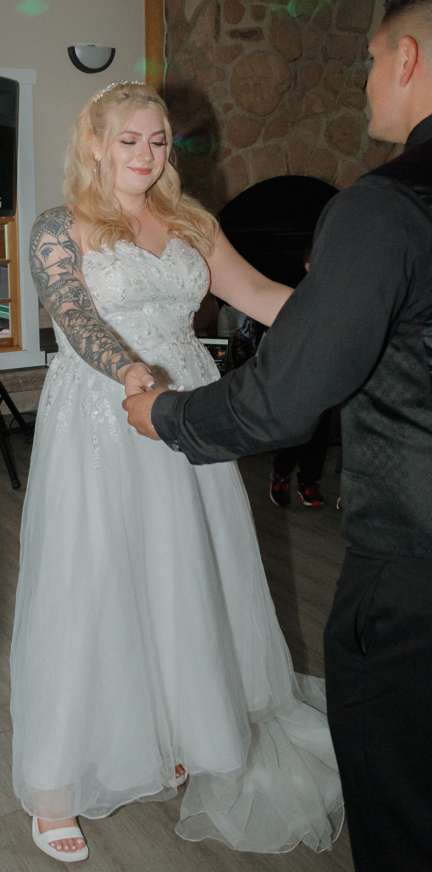 Wedding couple dancing in venue with stone fireplace and hardwood floors.