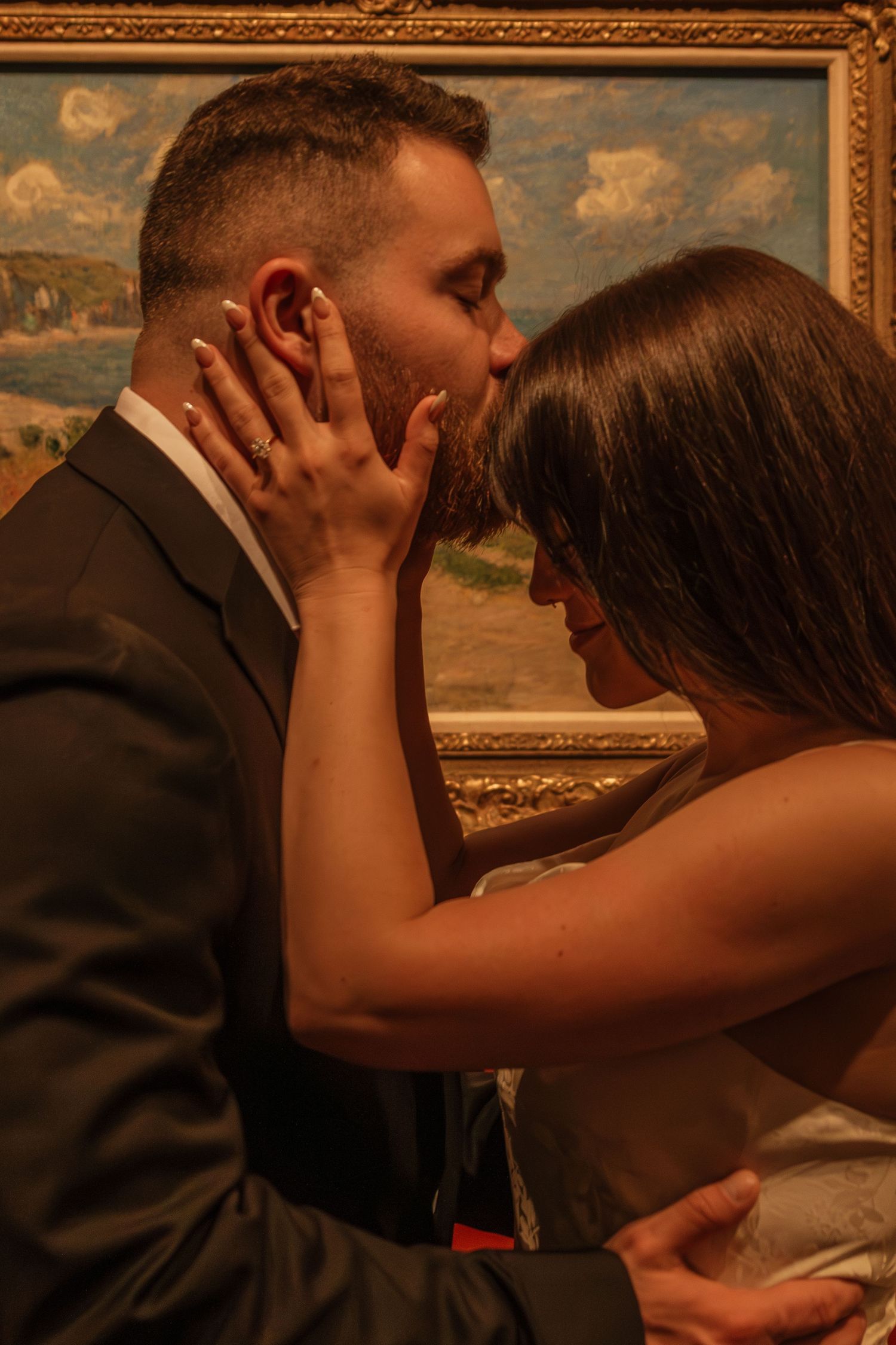 Romantic moment captured against an ornate gold frame and painted landscape background.
