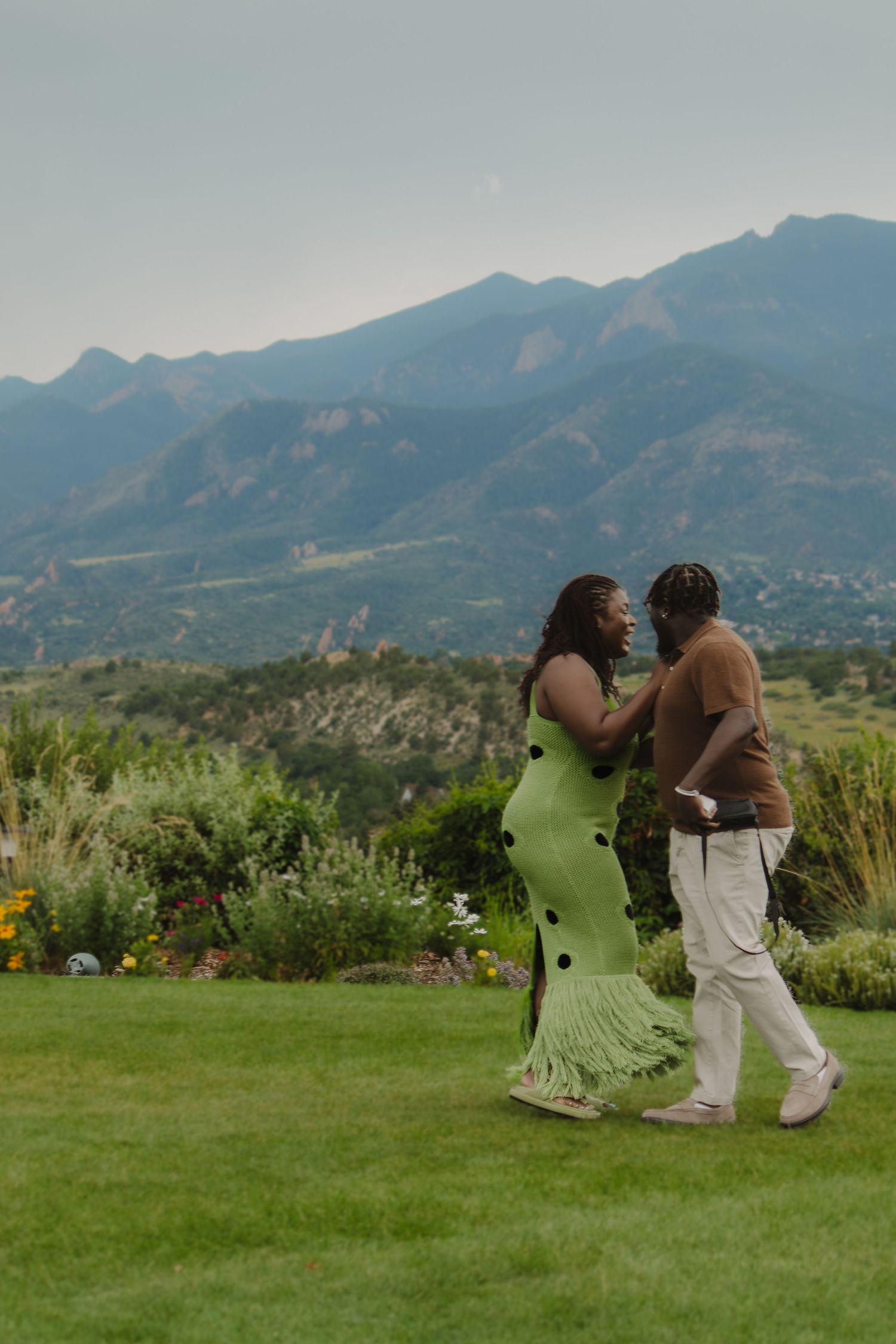 Couple dancing together on a grassy lawn with scenic mountain landscape in the background.