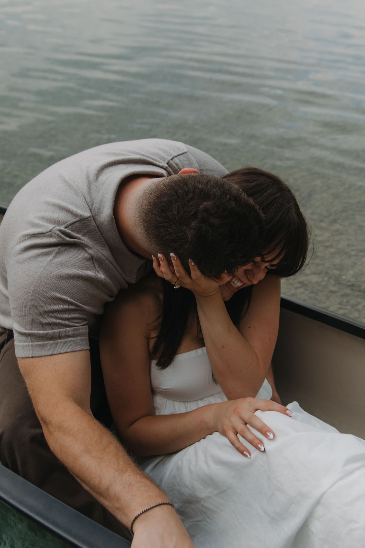 Couple shares gentle embraces while resting on white fabric in a boat.