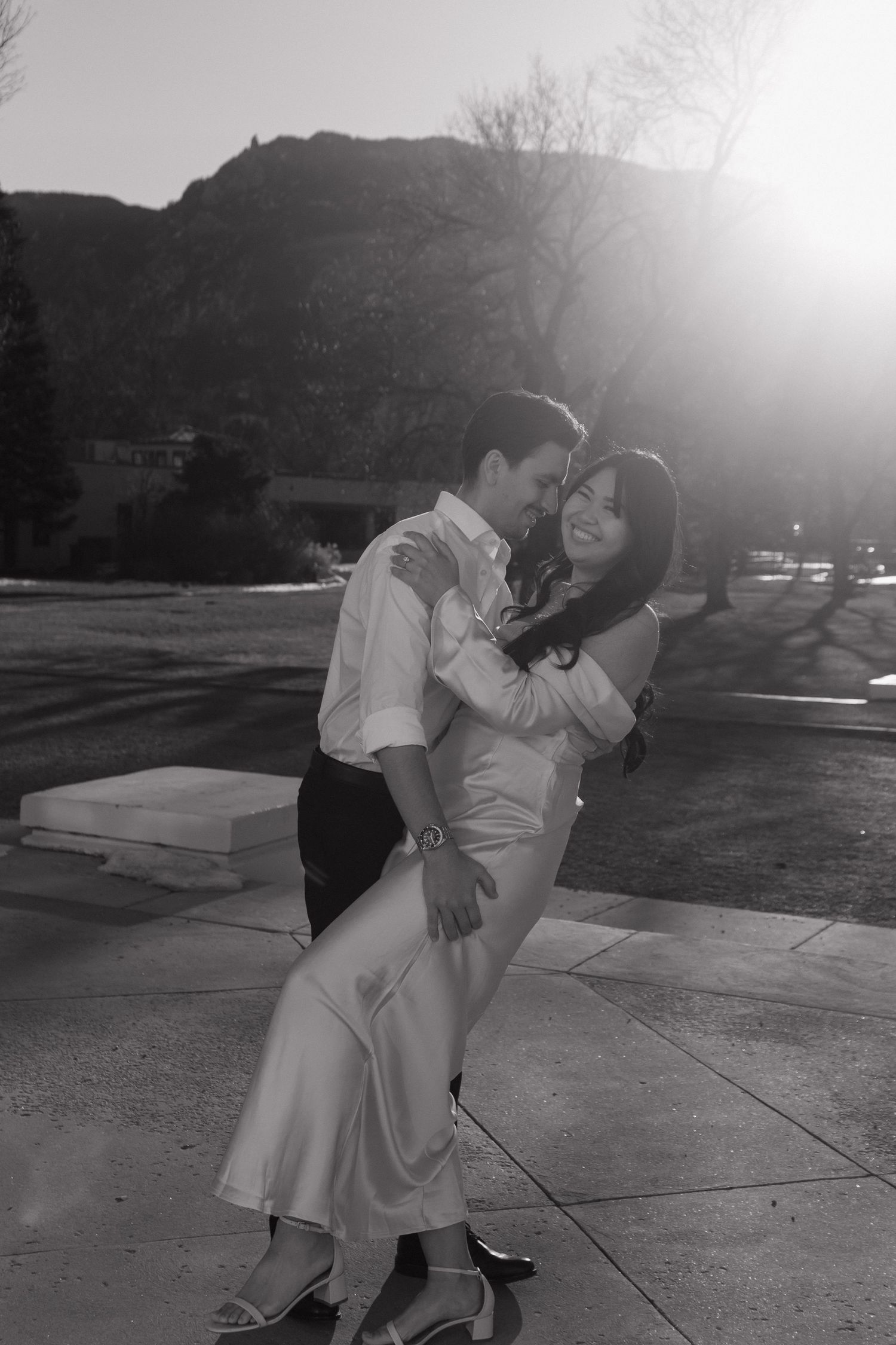 A black and white sequence showing a couple playfully interacting on a concrete surface in bright sunlight.