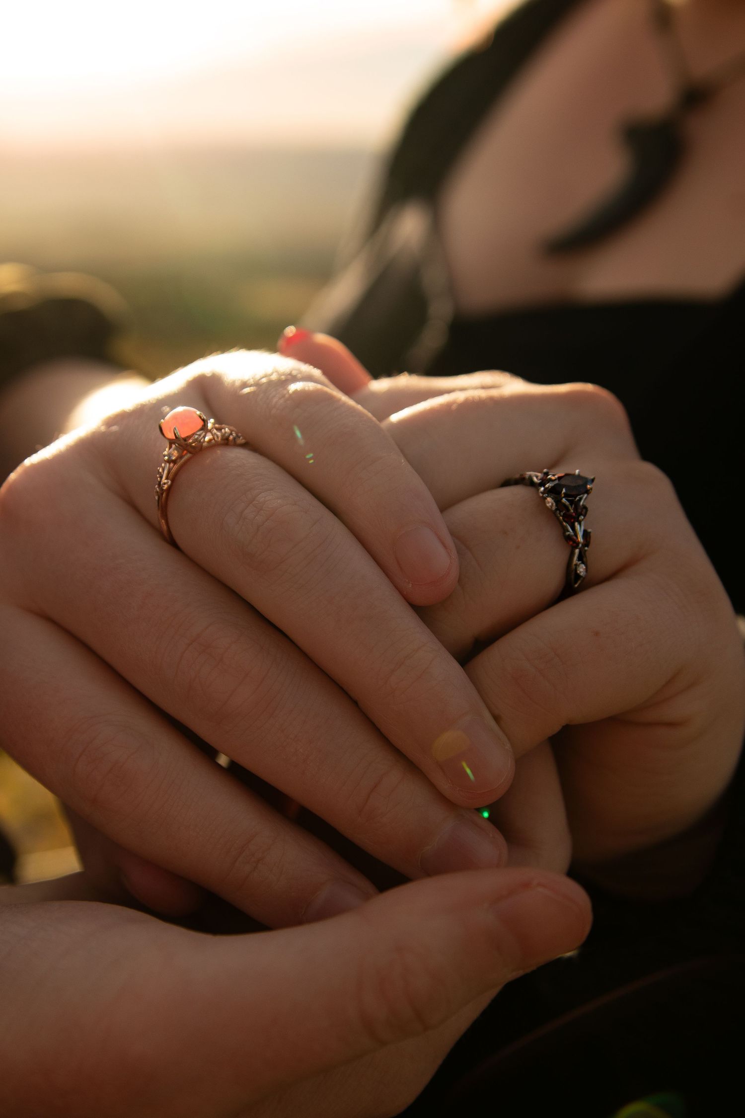 Close-up of hands wearing two ornate rings with golden light illuminating the delicate details.