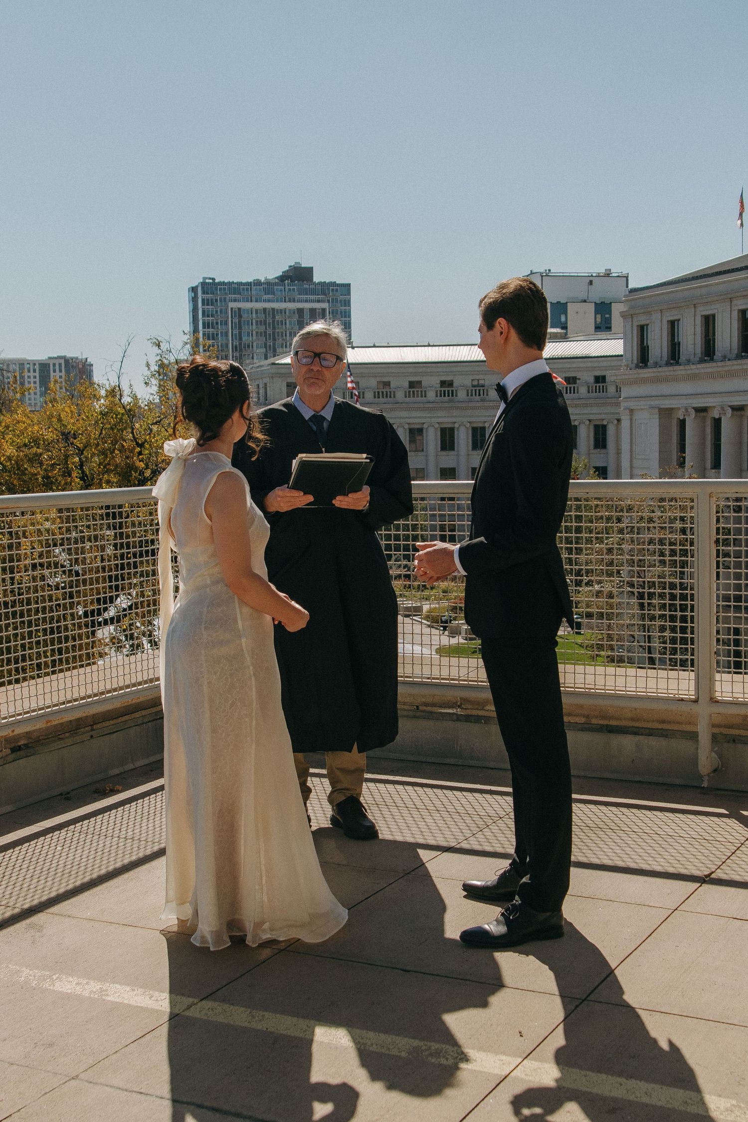 Outdoor rooftop wedding ceremony with city skyline in background.