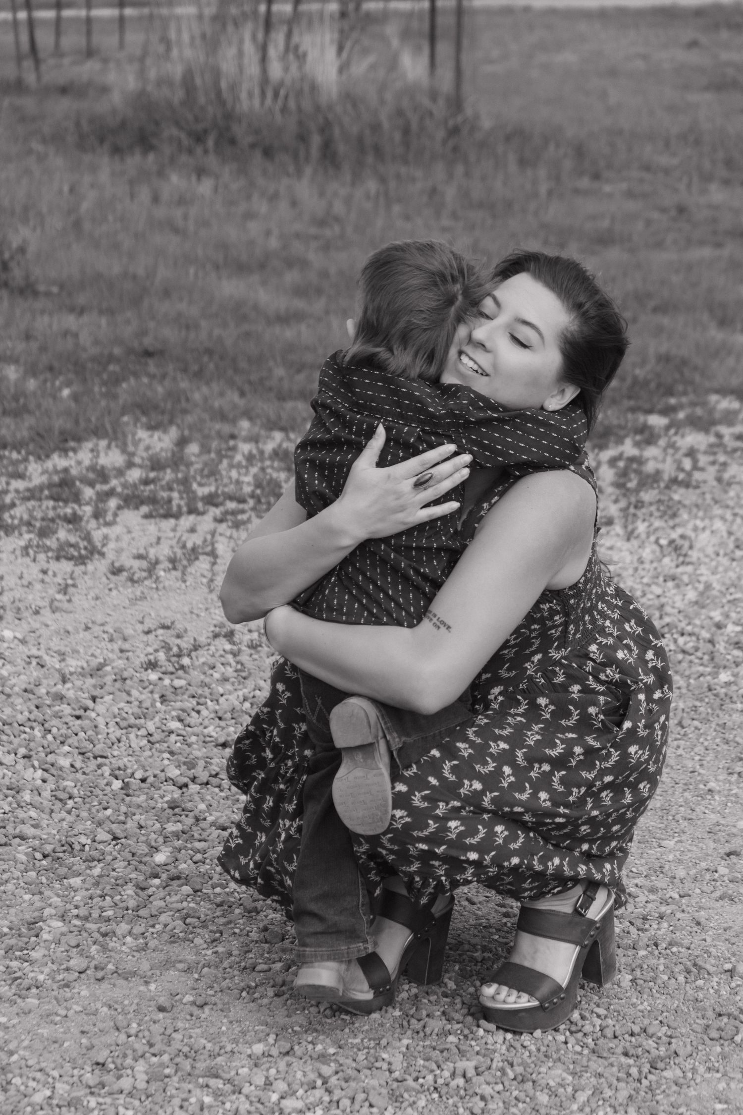 Black and white sequence showing emotional moments between people on a gravel surface.