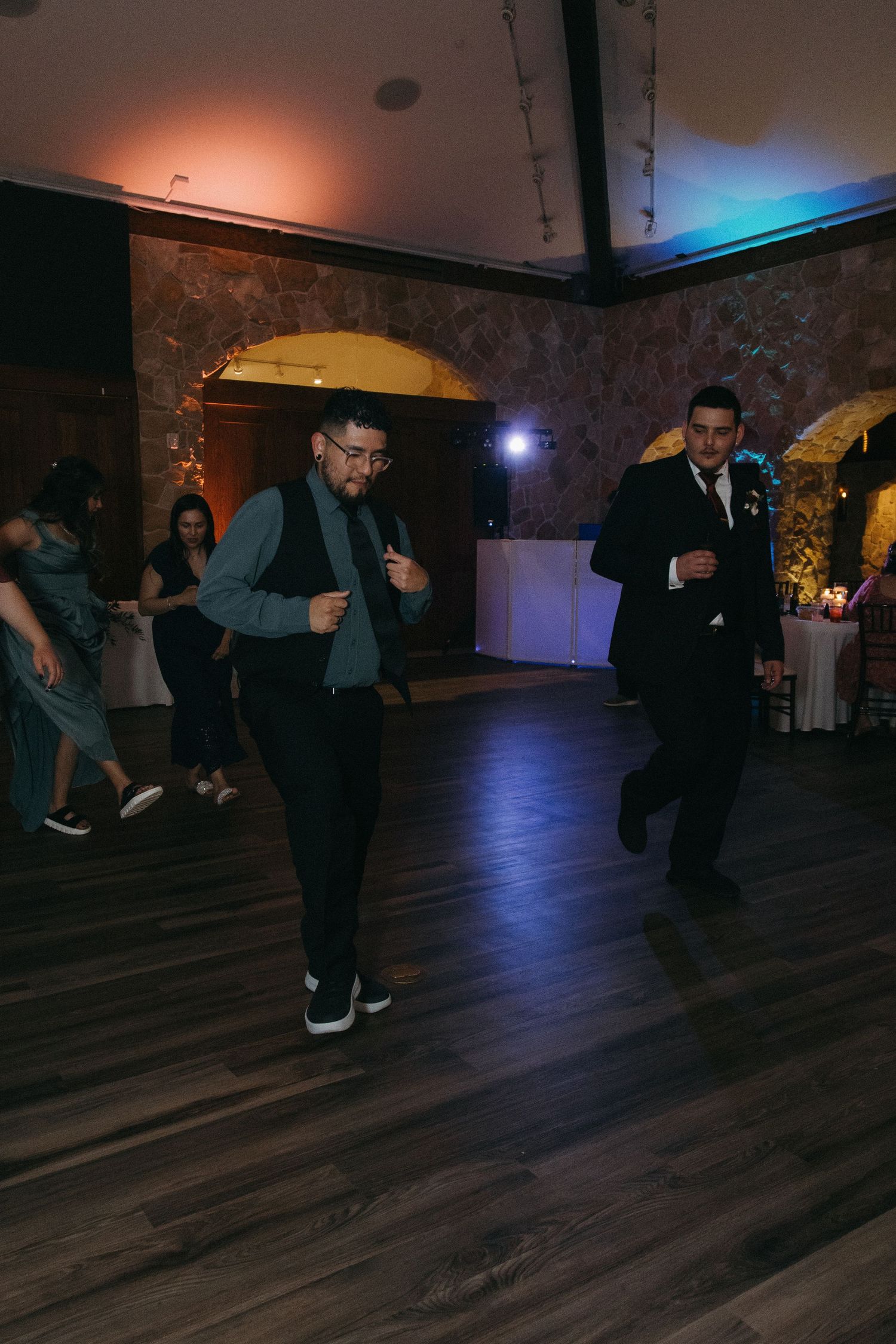Two men in suits dancing energetically on the dance floor at a wedding reception.