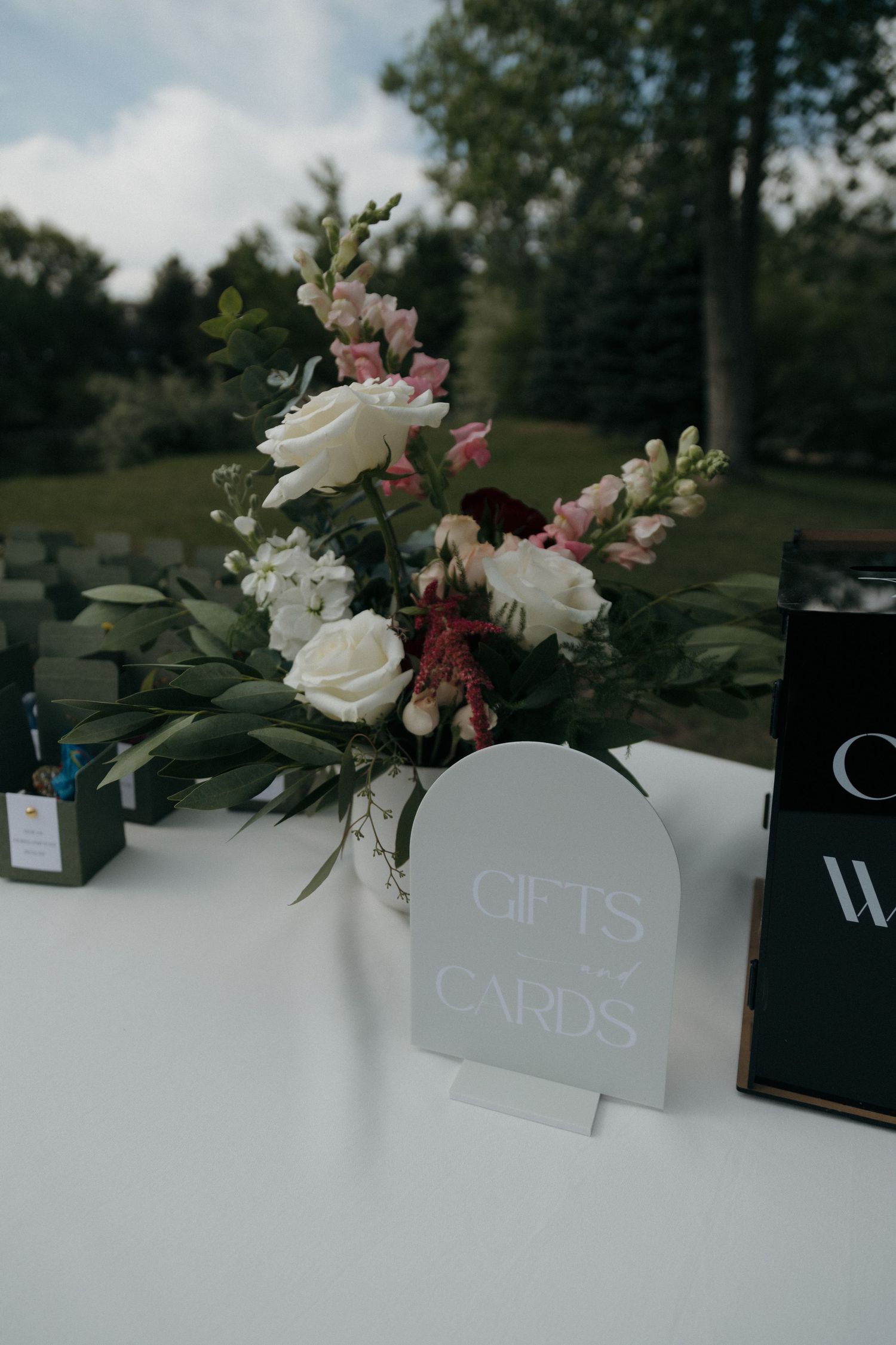 Wedding gifts and cards sign displayed beside white and red floral arrangement on reception table.