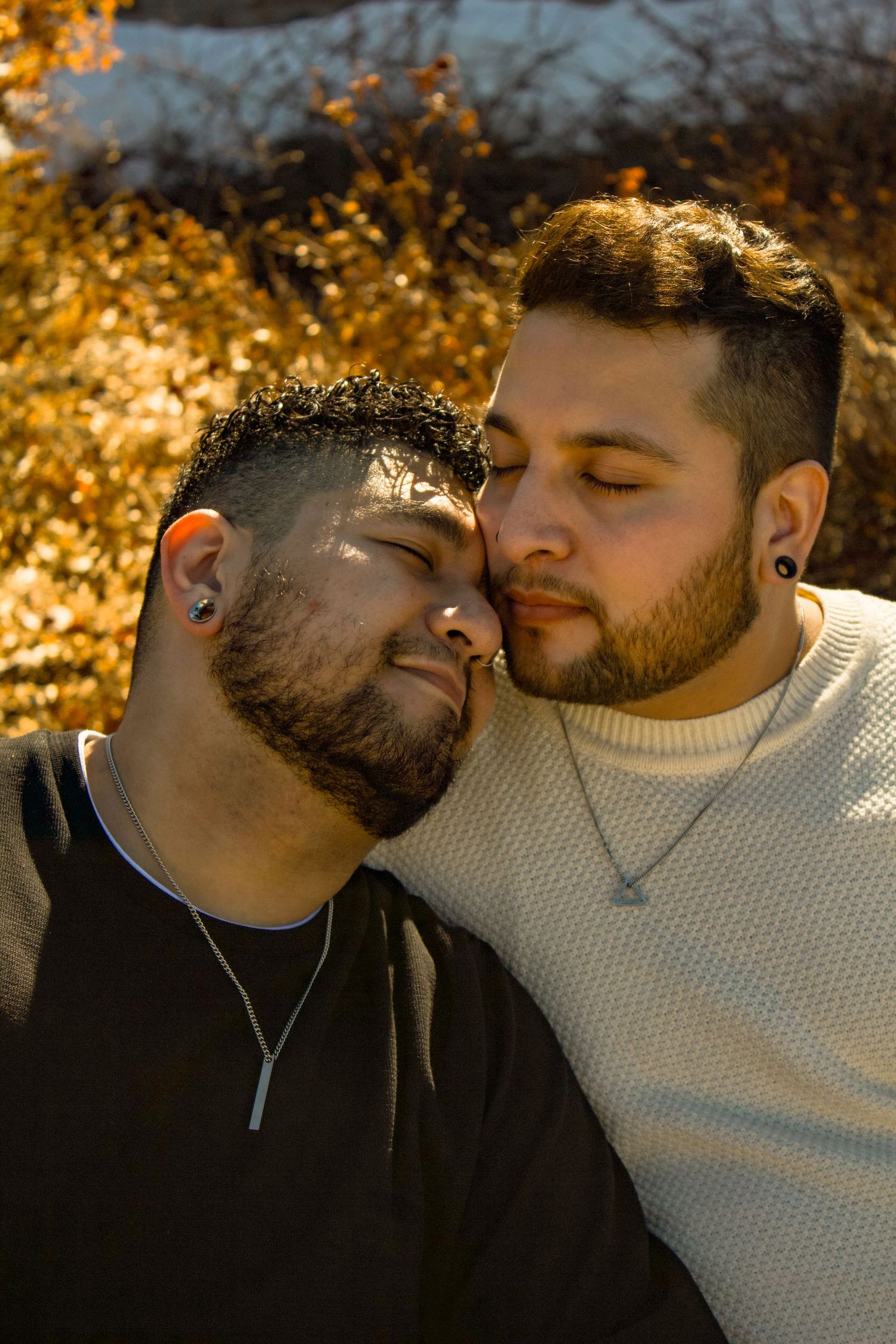 An intimate portrait of two people against golden autumn foliage and sunlight.