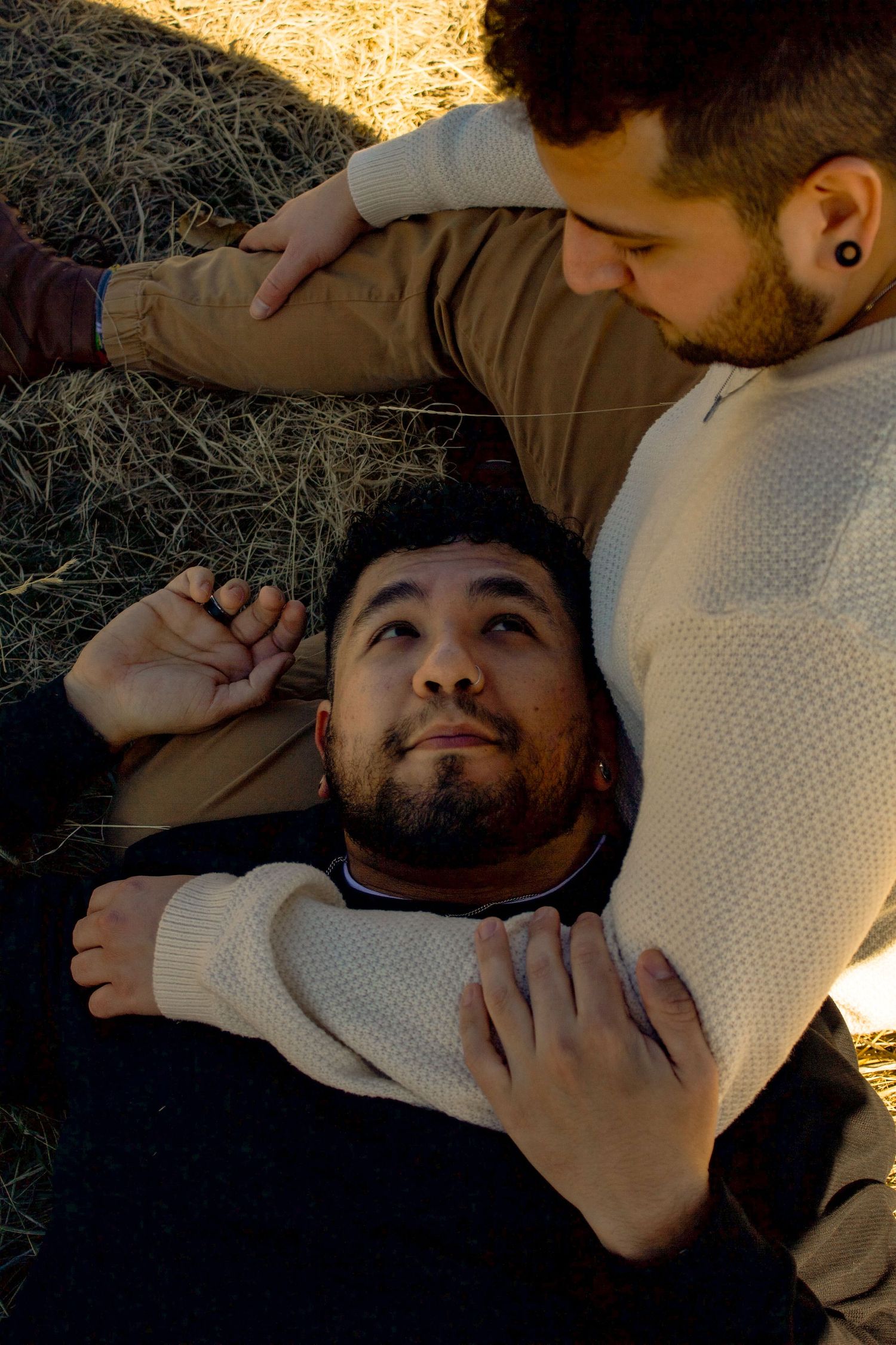 Two people sharing an intimate moment while resting on hay during golden hour.