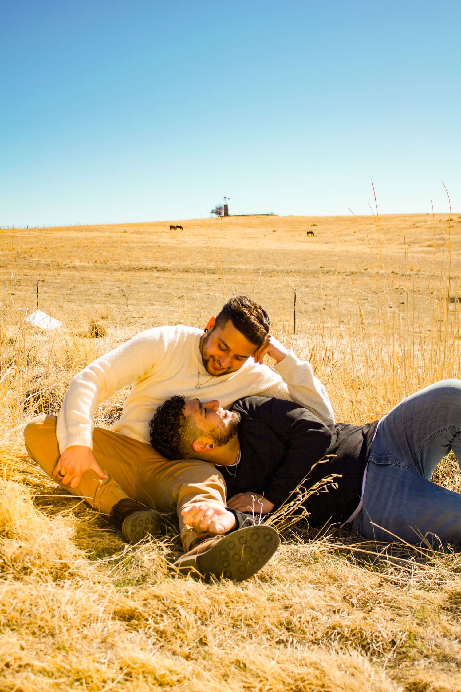 Two people sharing tender moment while lying in sun-drenched field.