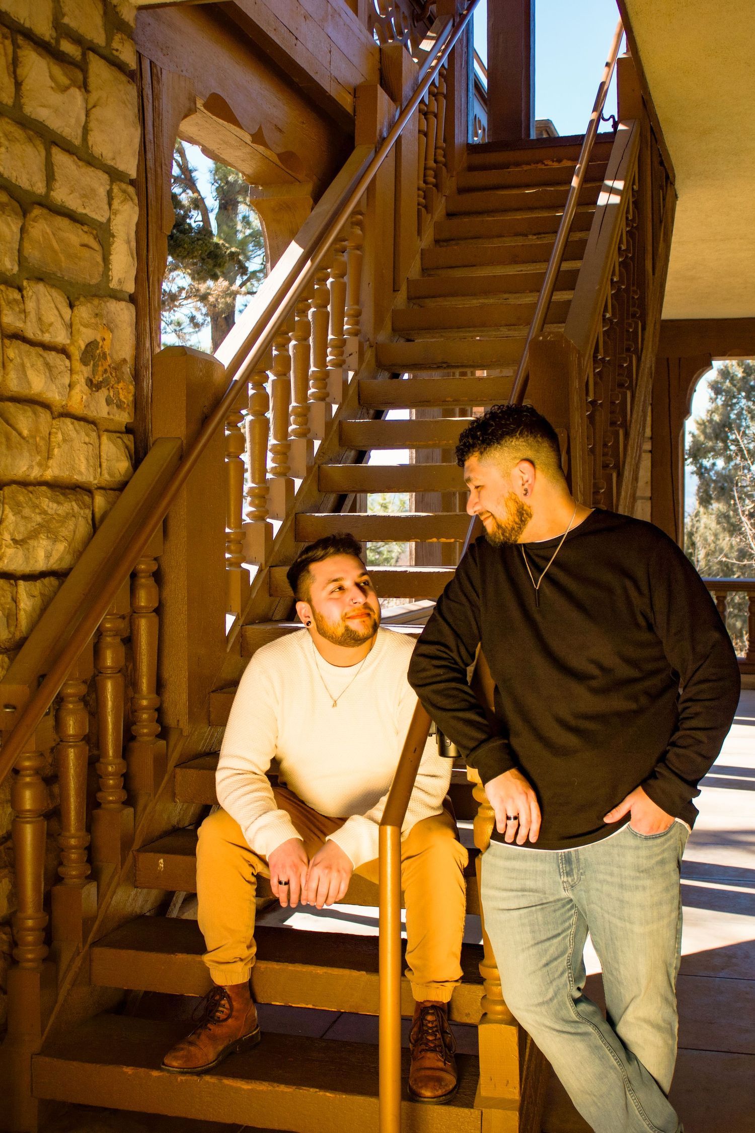 Two people sitting and standing on wooden stairs having a conversation.