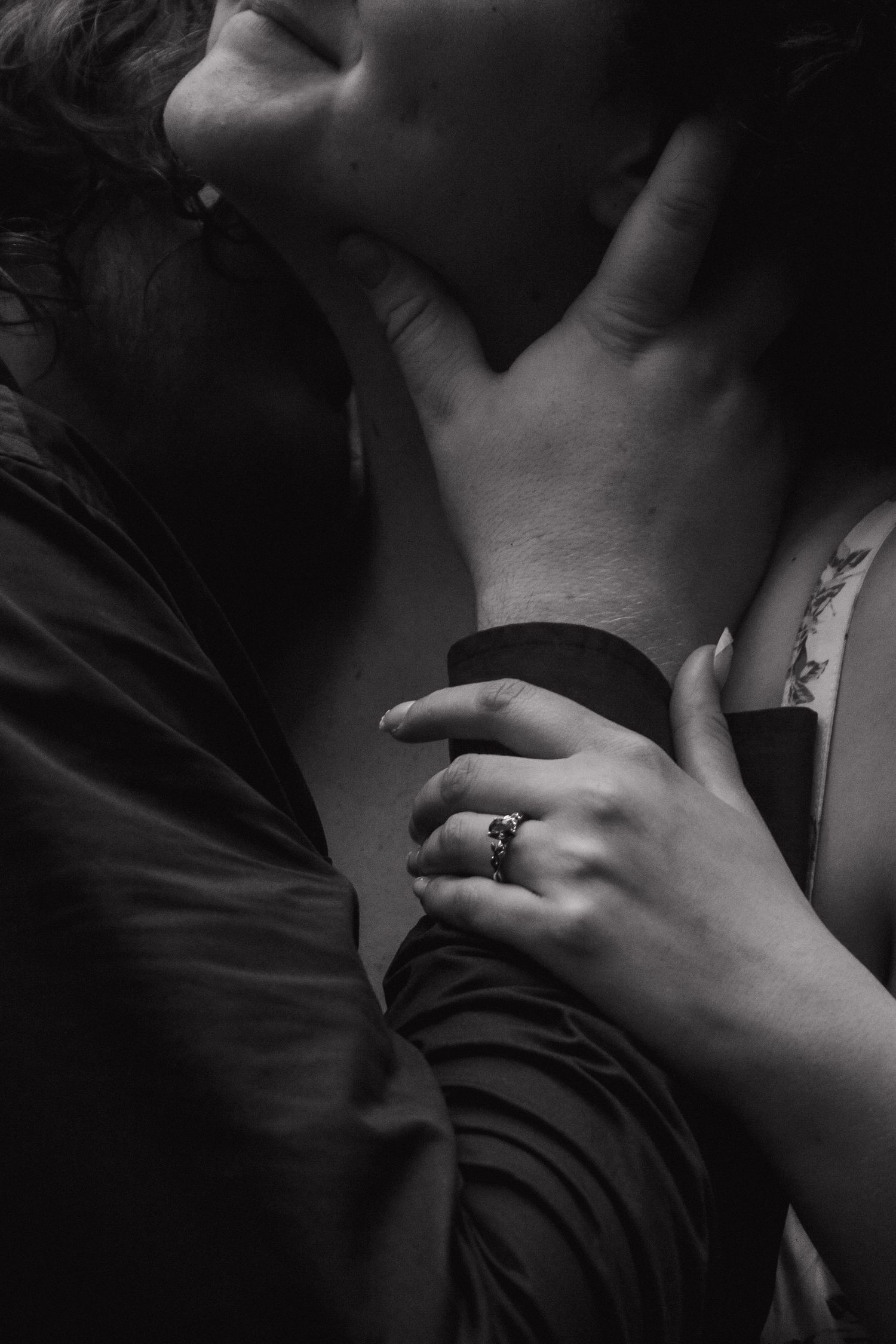 A close-up black and white shot showing hands and intimate embrace of a couple.