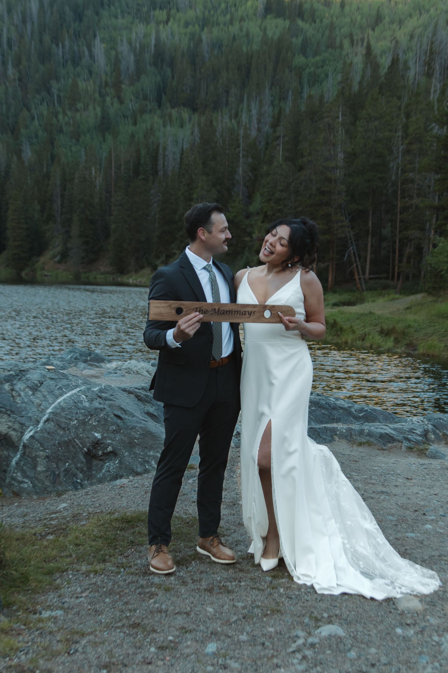 A couple in wedding attire shares romantic moments by a lakeside forest setting, captured in a sequence of candid shots.