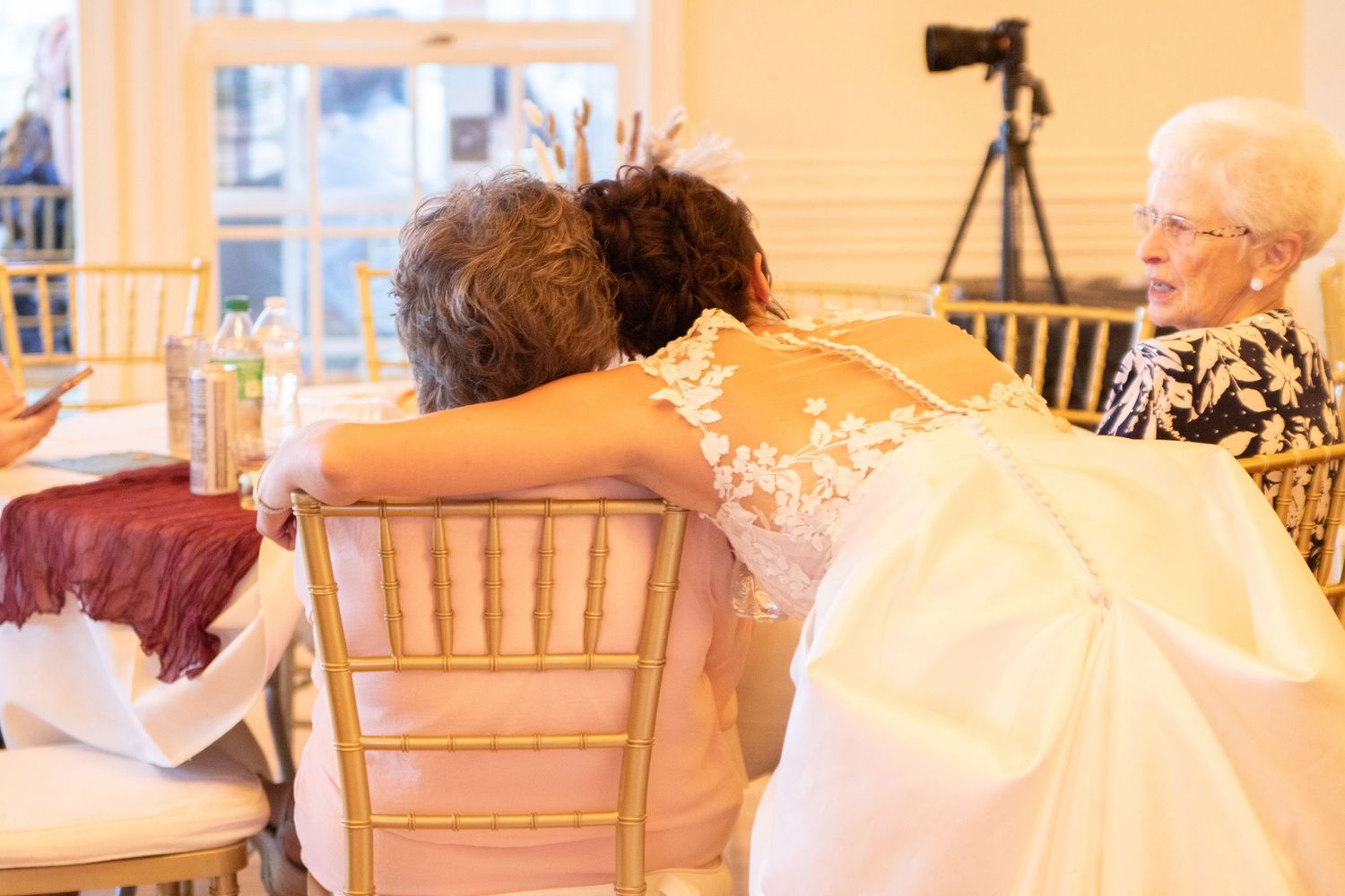 Wedding reception guests seated at tables in warm-lit venue with golden decor.