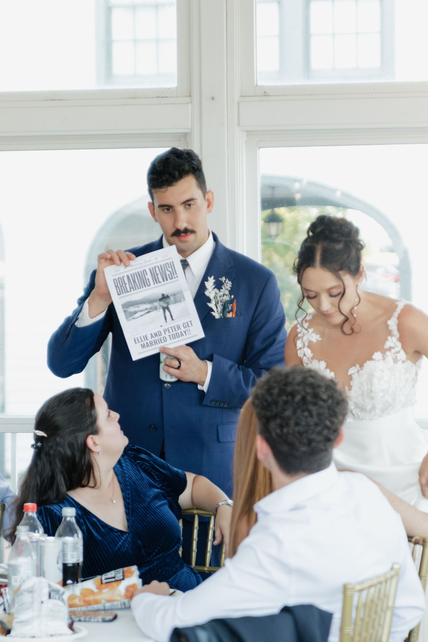 Wedding reception scene with guests reacting to cards being held up during a fun game or activity.