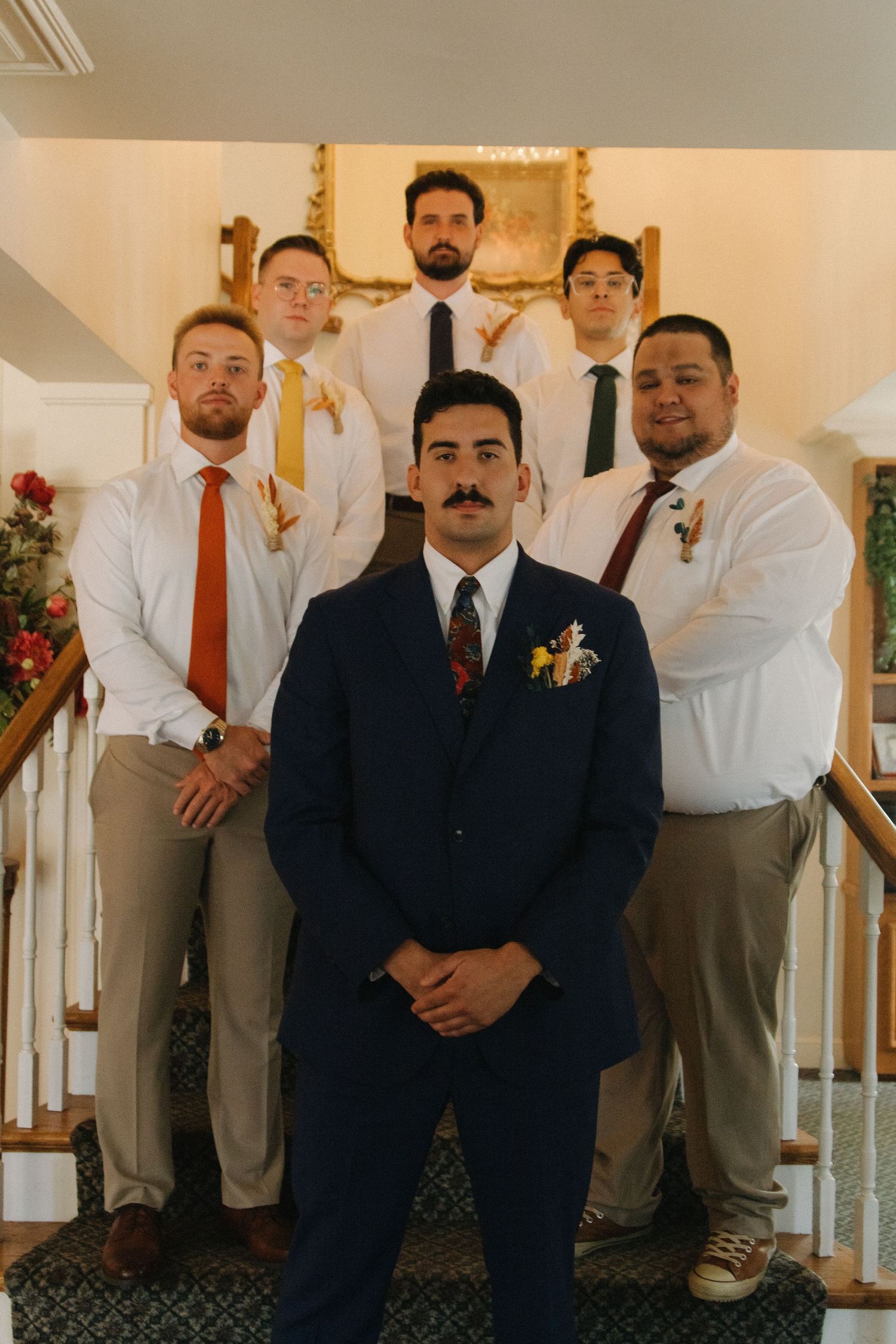 Groomsmen in formal attire pose together for a wedding party photo.