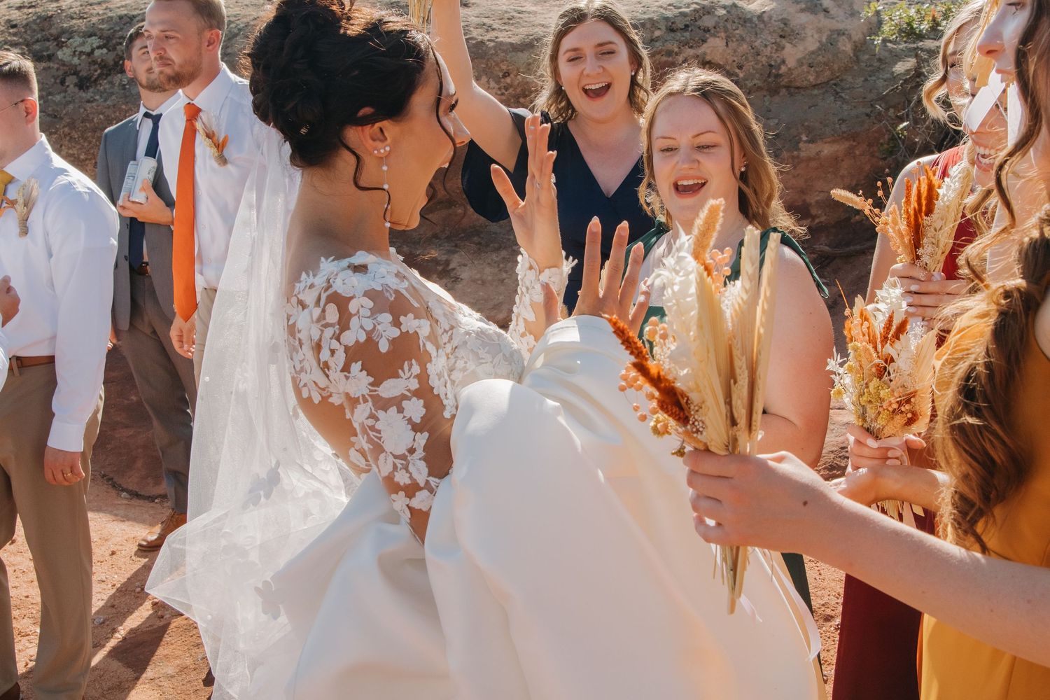 Wedding party celebrates outdoors against a backdrop of scenic red rock formations.