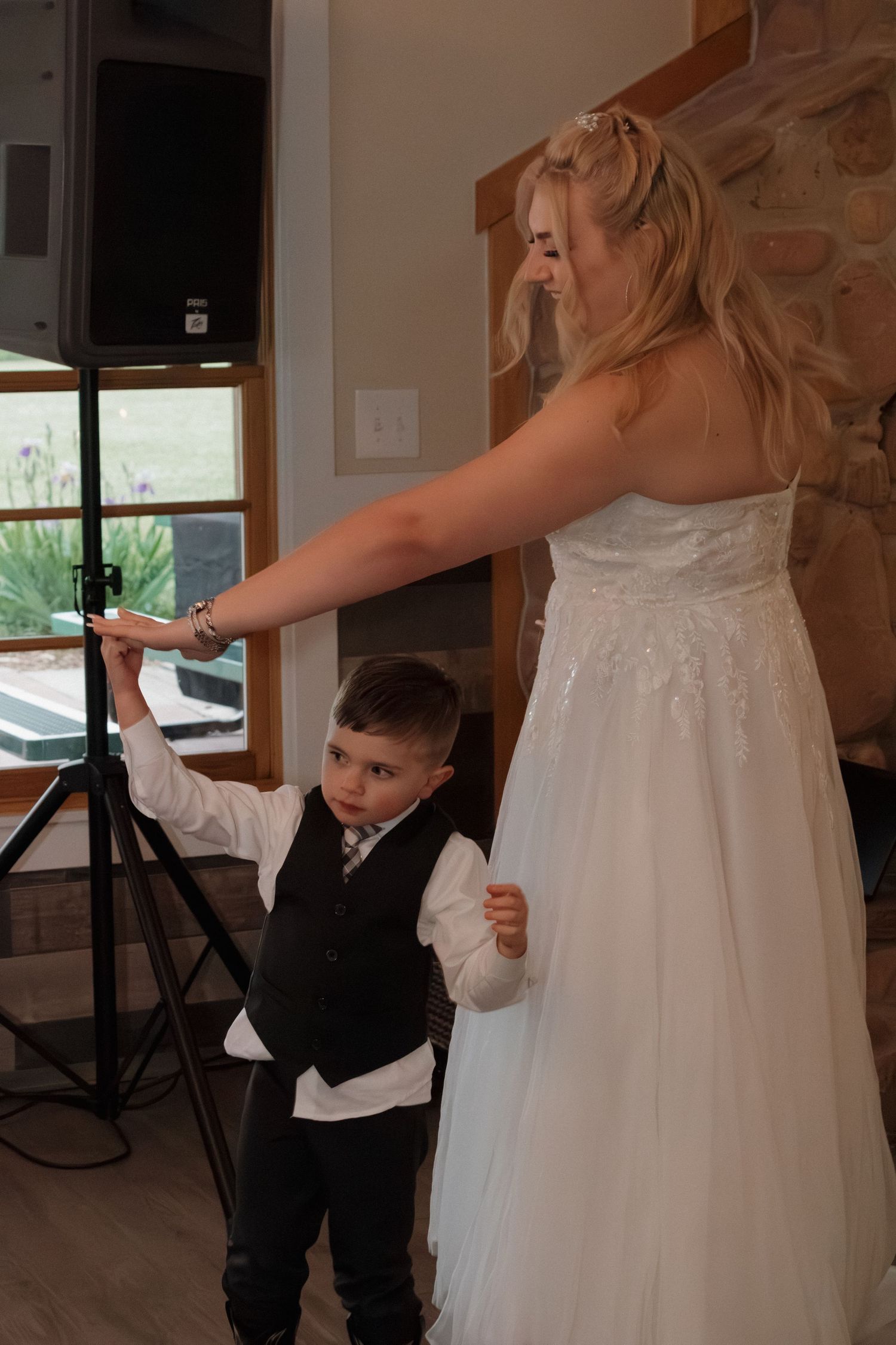 Young ring bearer in formal suit interacting with bride in white wedding dress.