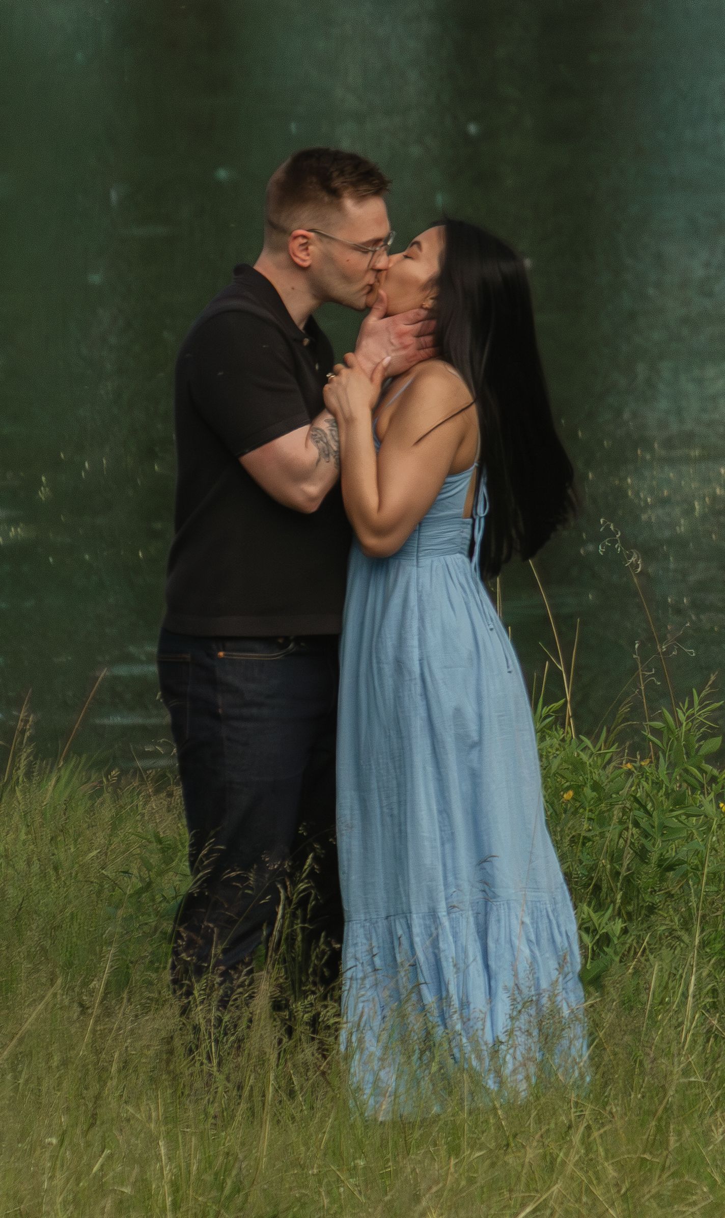 Intimate outdoor portrait session in a natural setting with water and grassland scenery.