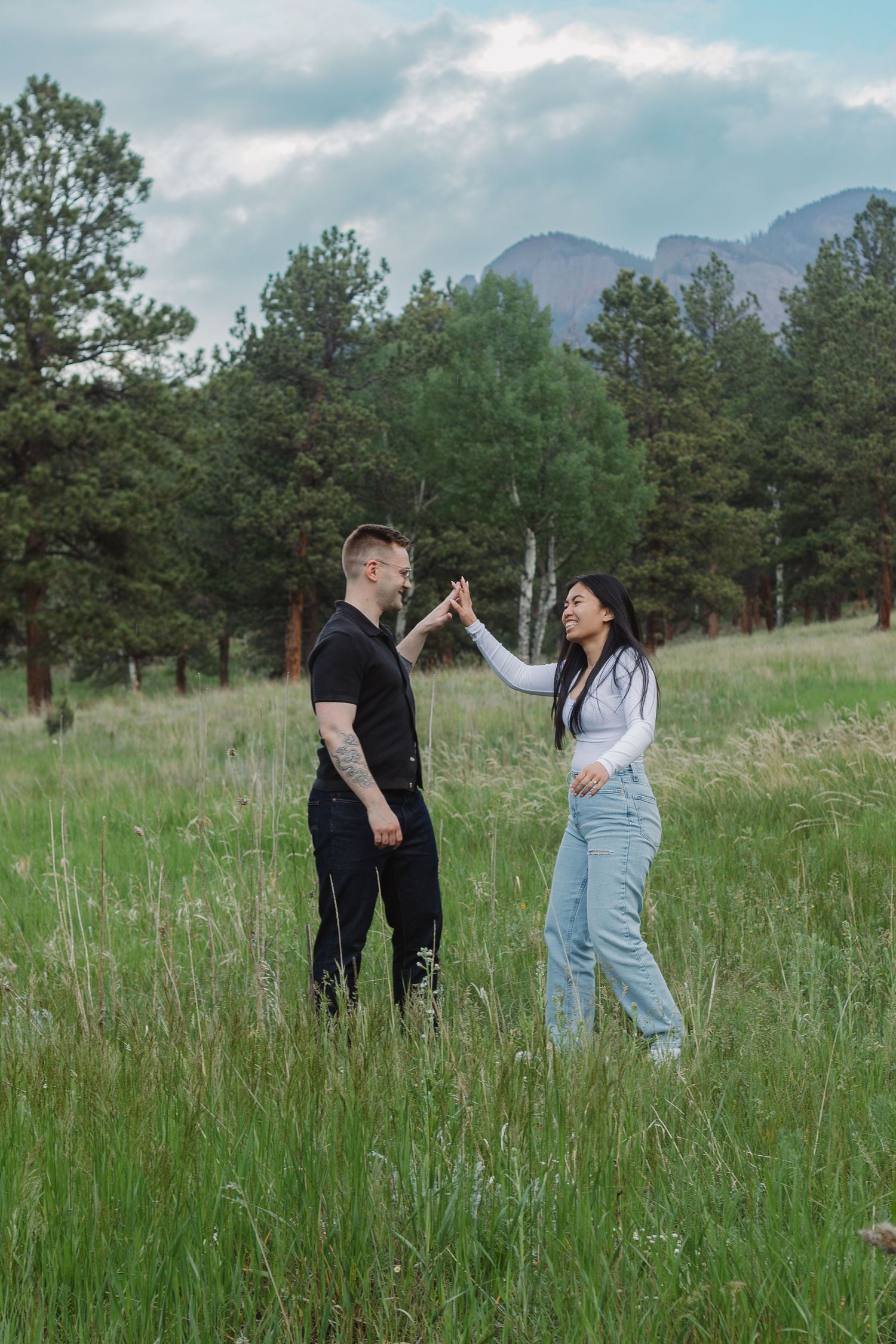 A couple gives each other a high five while enjoying a moment in a mountain meadow.