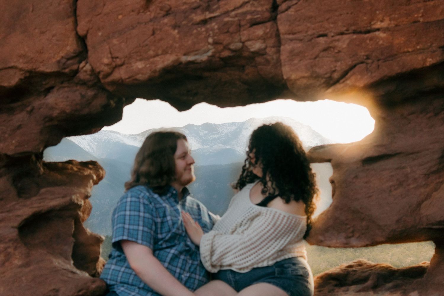 Silhouetted figures framed by natural rock archway during golden hour.