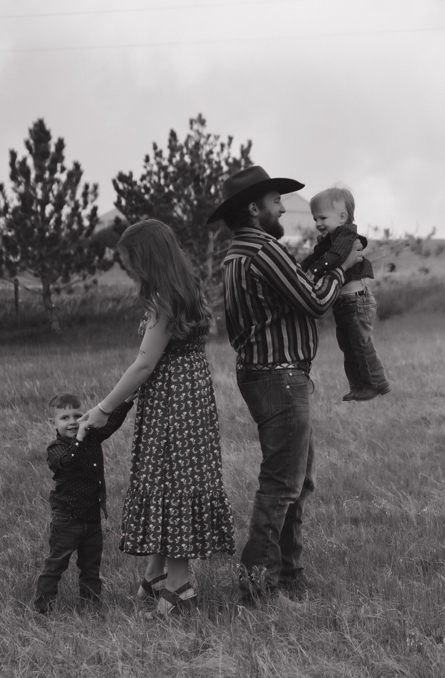 Black and white portrait of a family spending time together in a rural field setting.