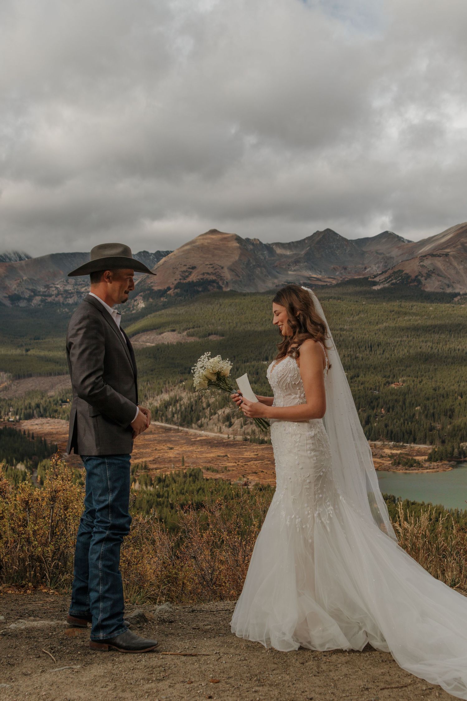 Wedding couple exchanging vows against a dramatic mountain backdrop with lake views.