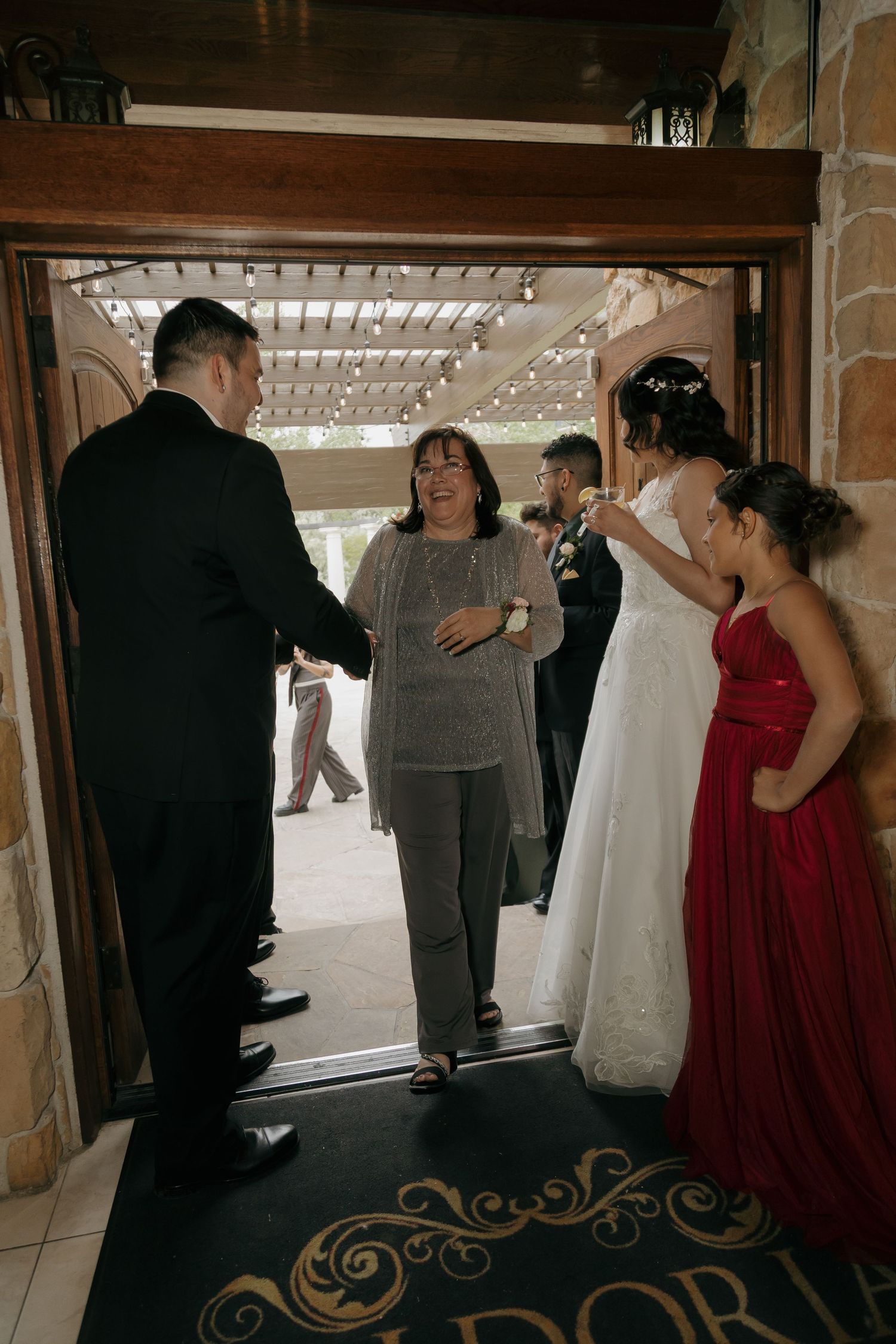 Wedding guests greeting the bride and groom at the entrance of an elegant venue.