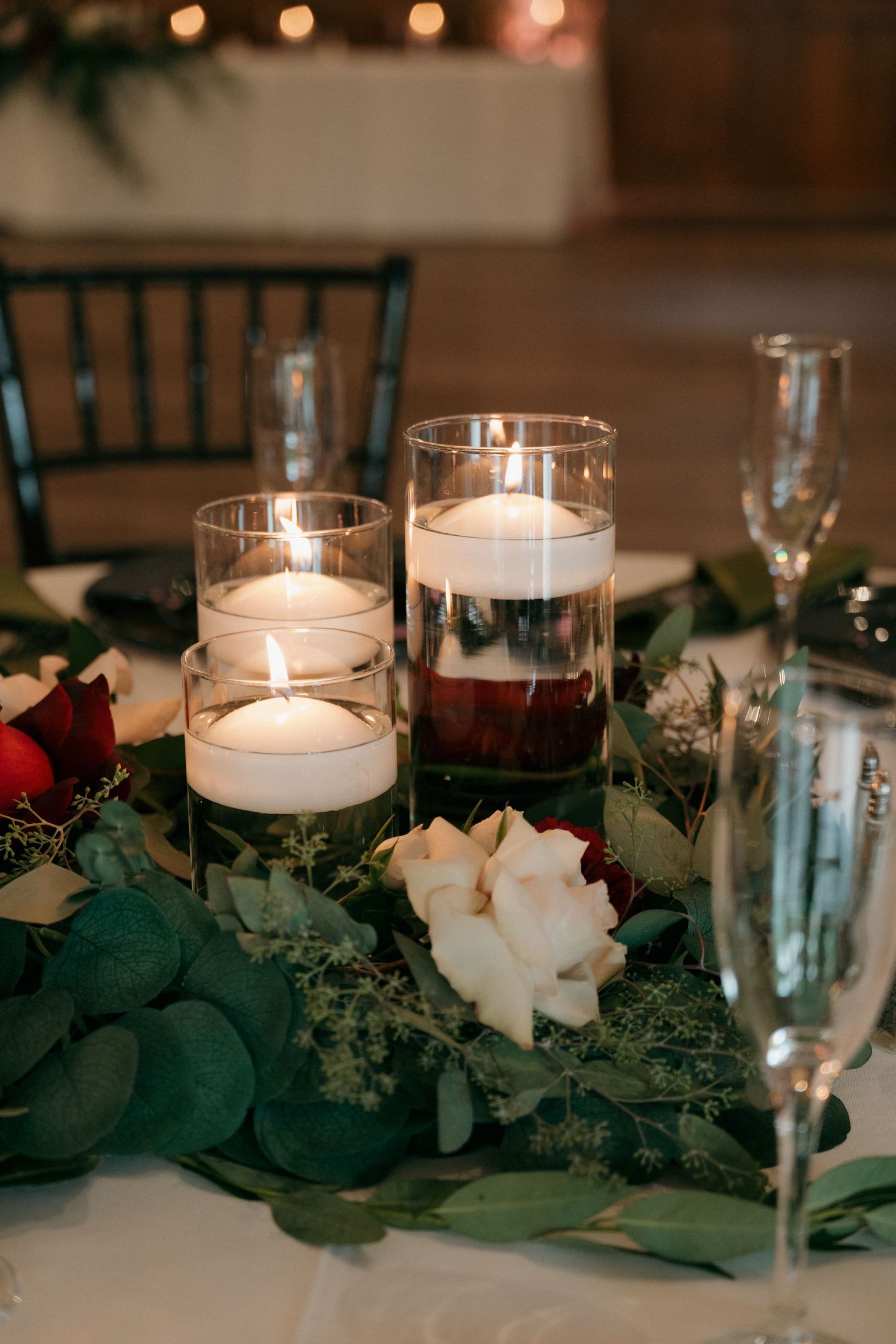 Romantic wedding table centerpiece with floating candles, white roses, and greenery.