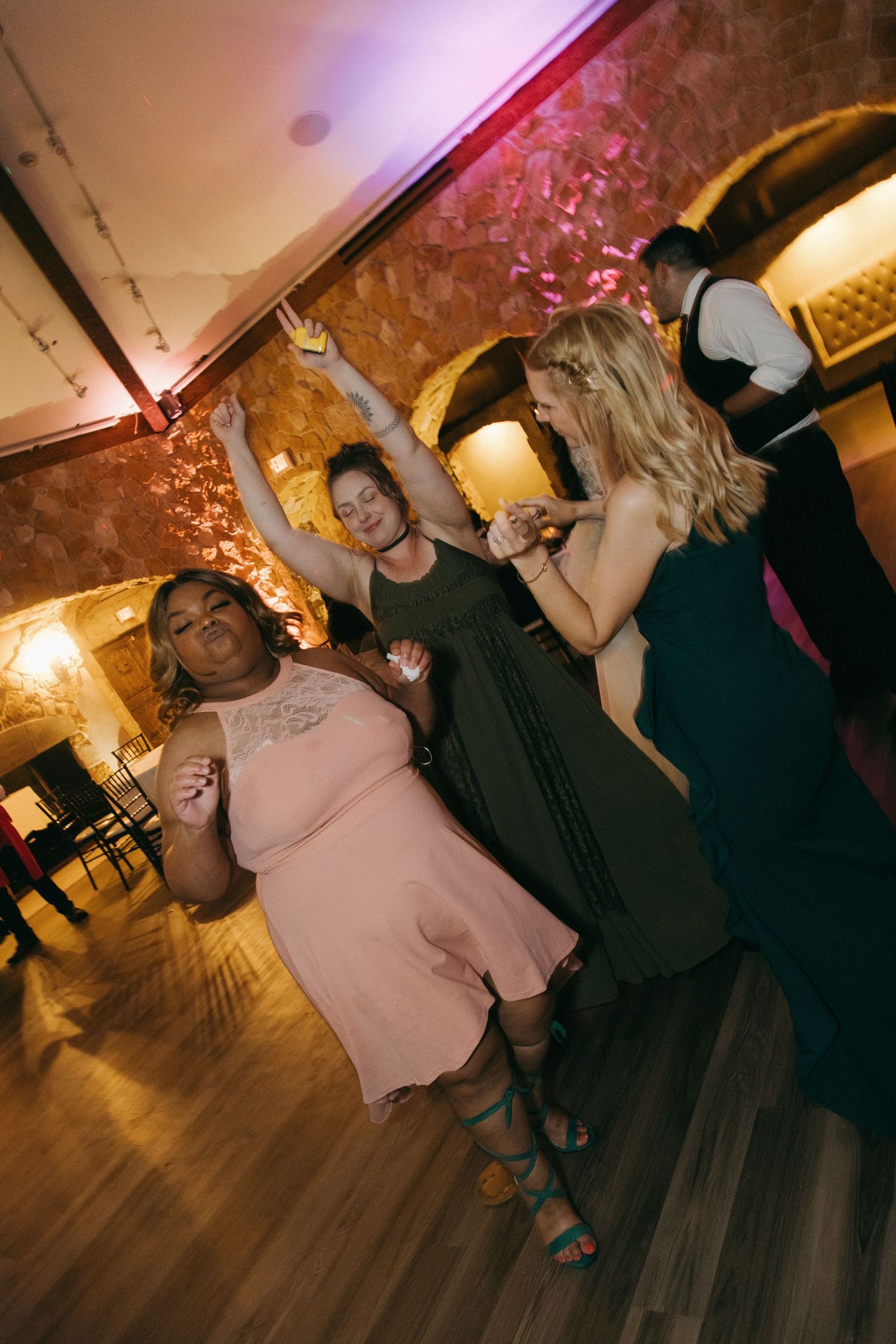 Wedding guests dancing joyfully on the dance floor at a lively reception celebration.