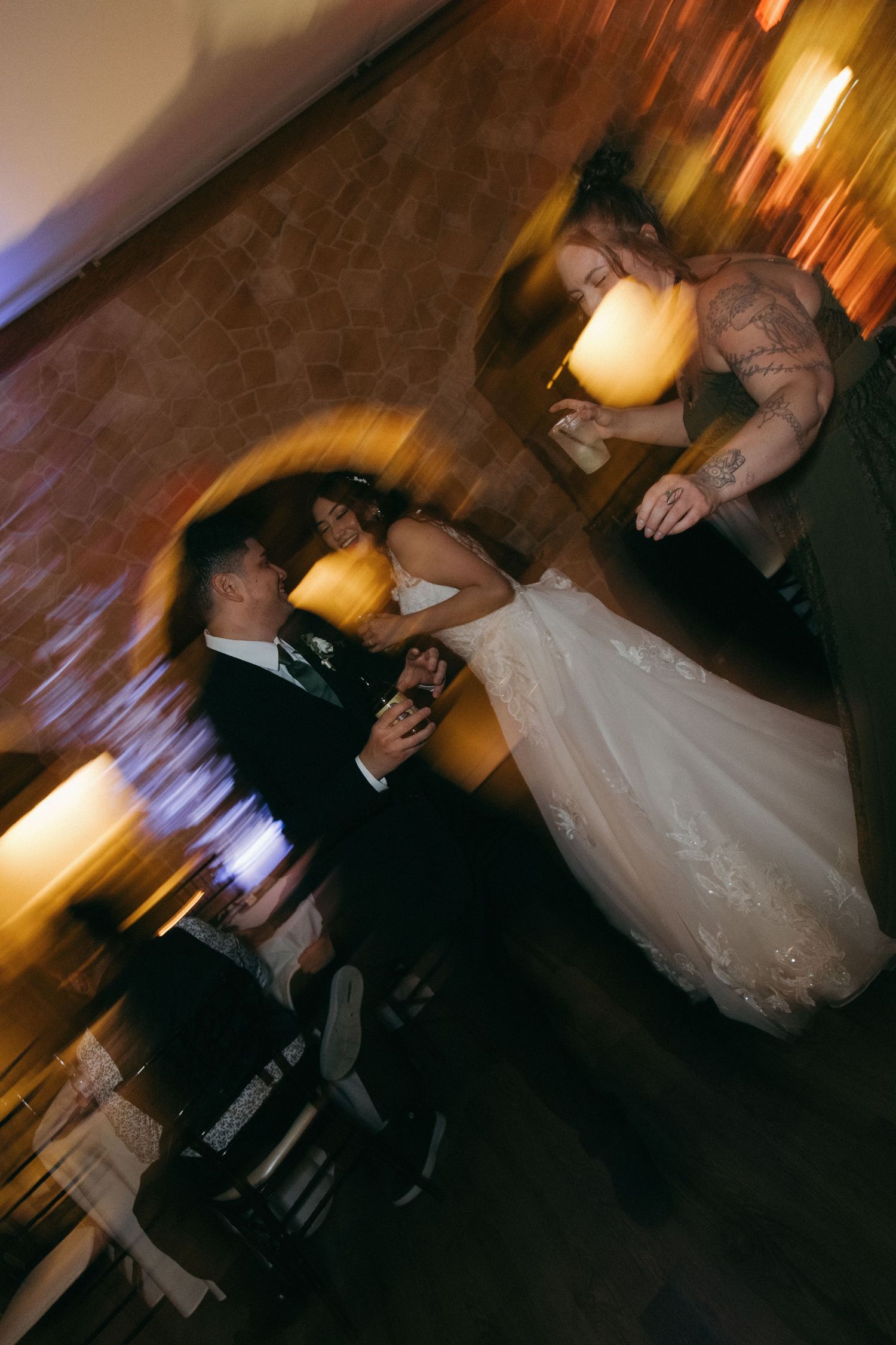 Bride and groom share first dance in warmly lit reception hall with motion blur effect.