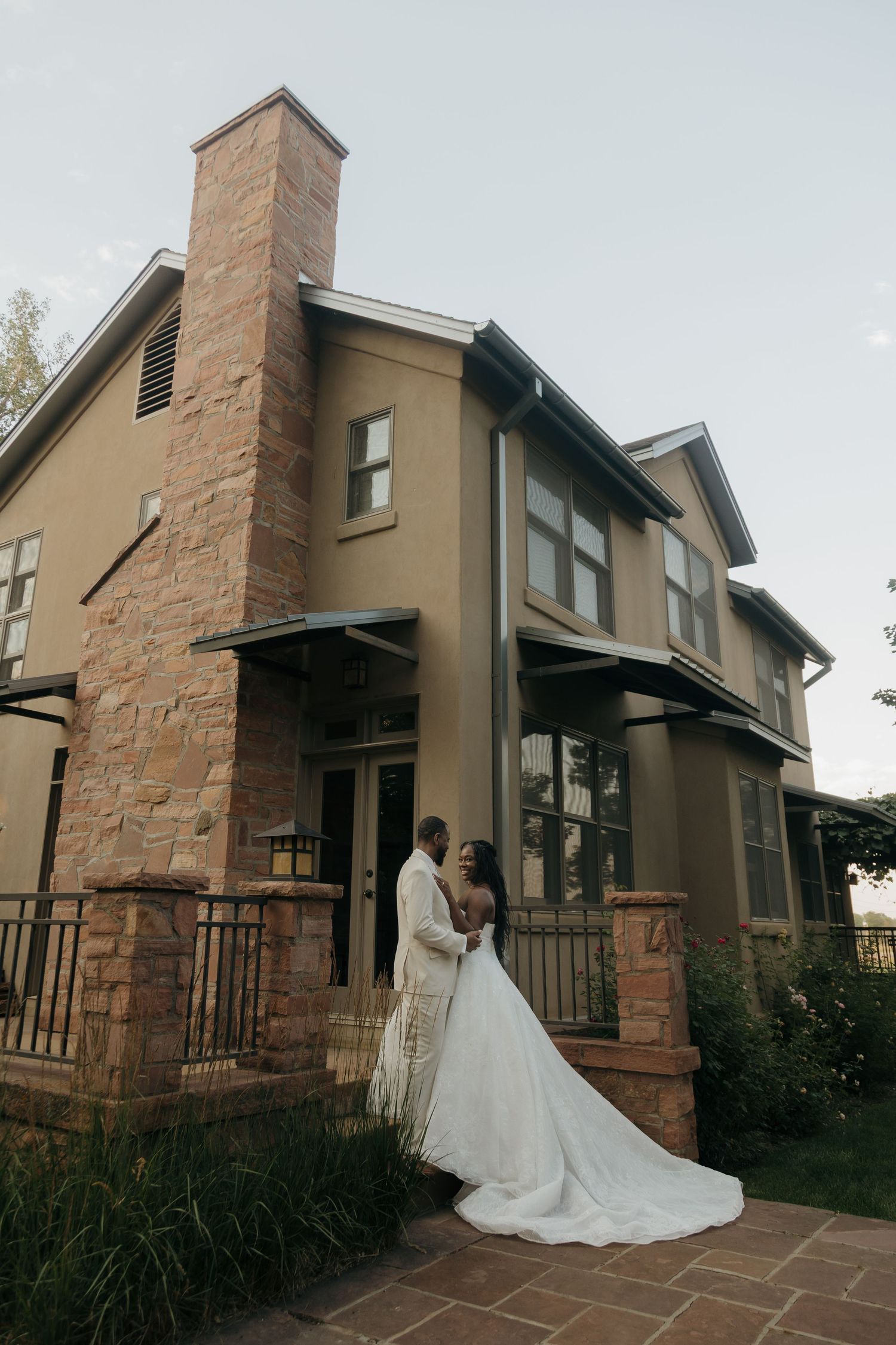 Bride and groom posing together in front of an elegant stone and stucco wedding venue.