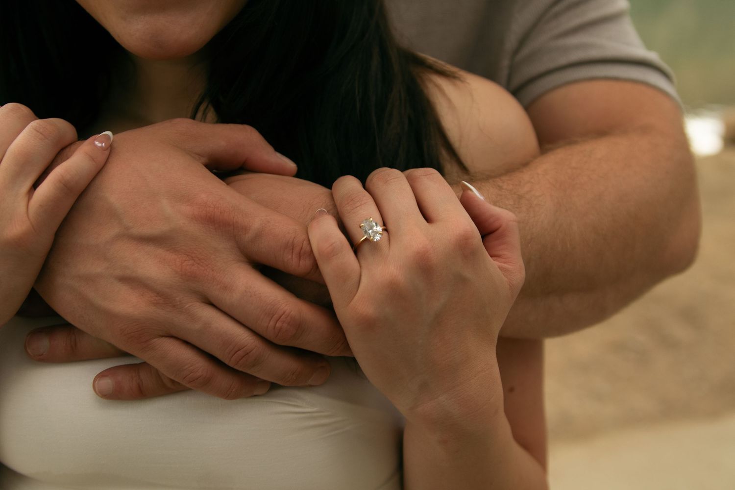 Close up photo of hands holding gently across a table in an indoor restaurant setting.