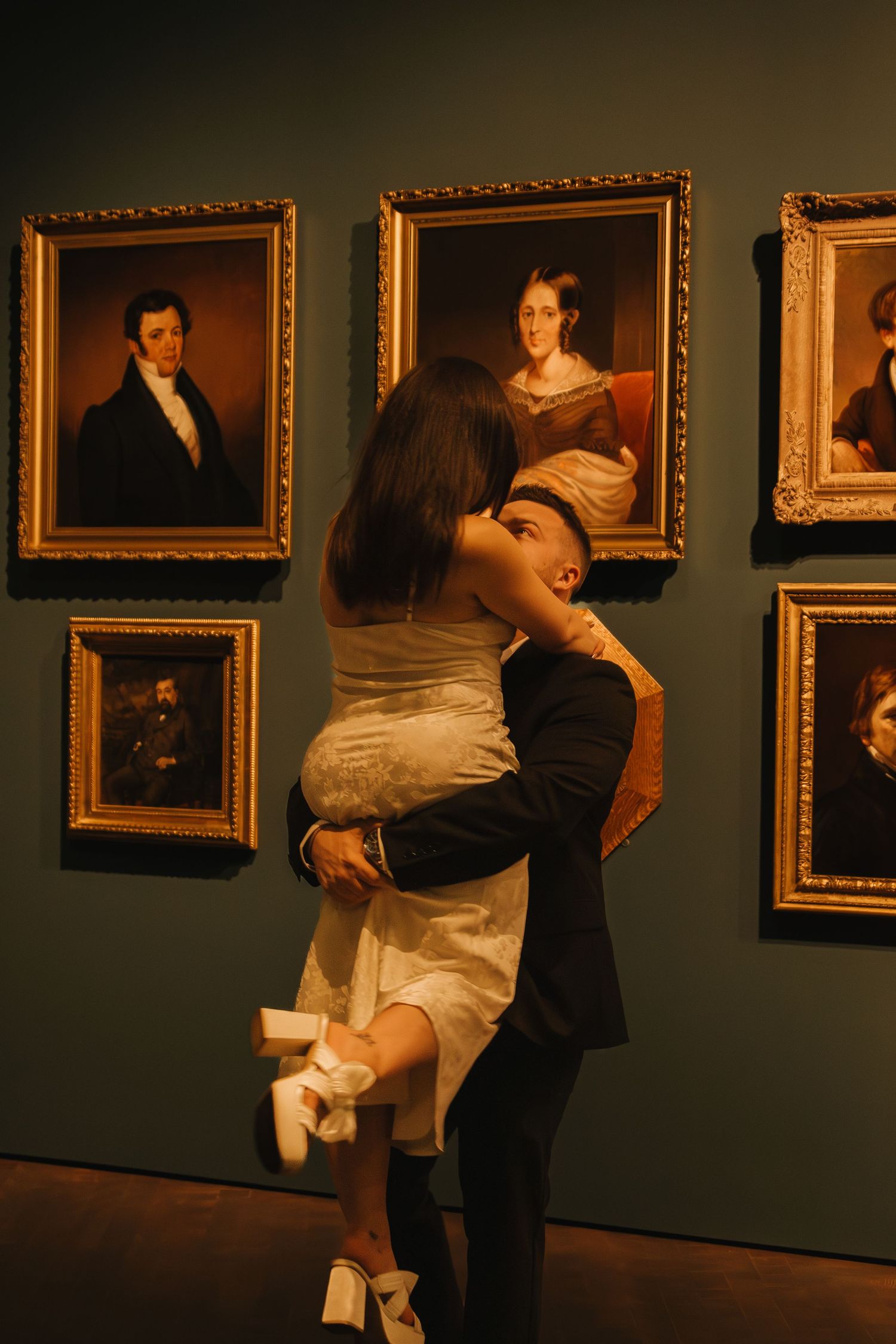 A romantic dance in an art gallery with vintage portraits lining the dark green walls.