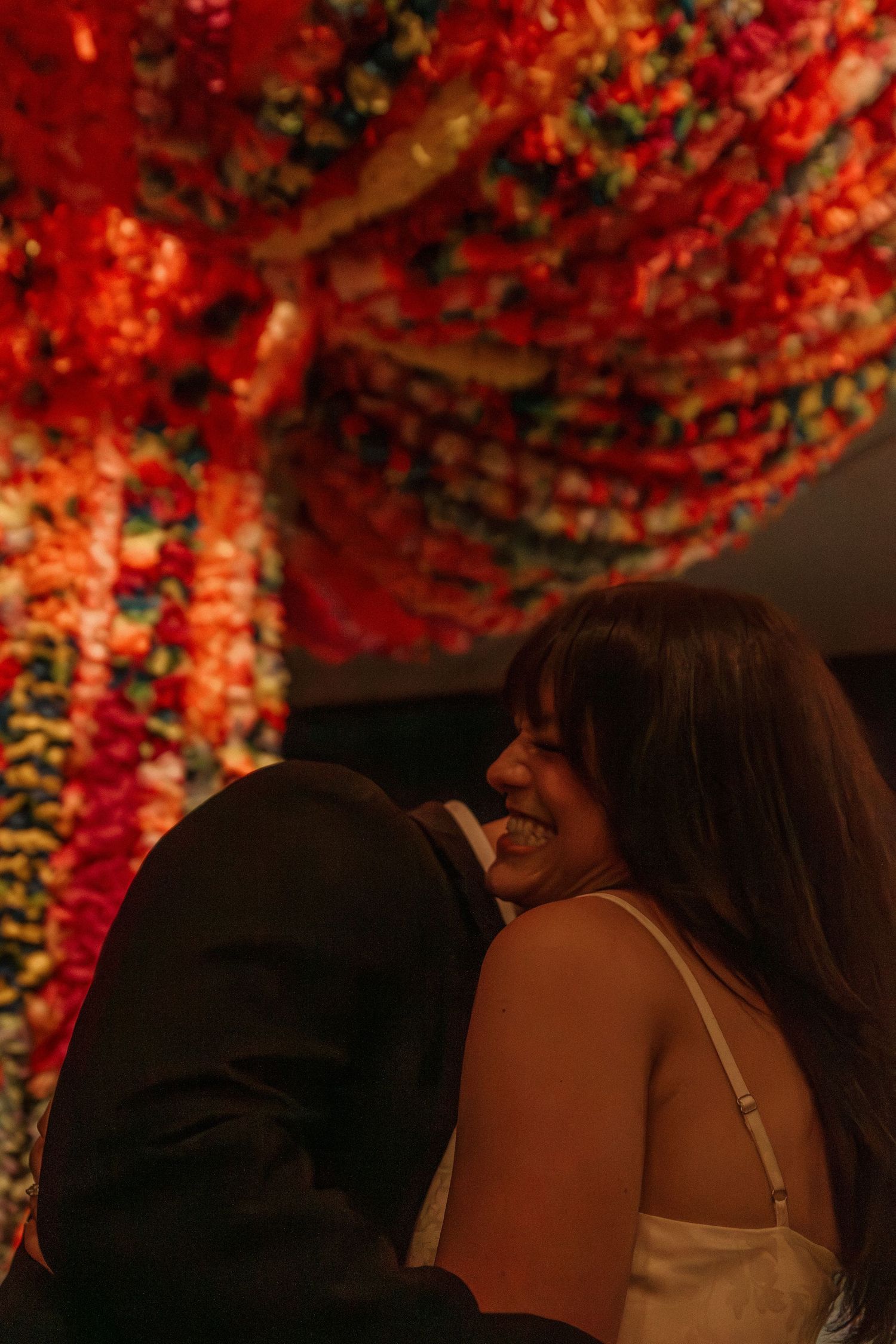 A romantic moment captured under vibrant red floral decorations.