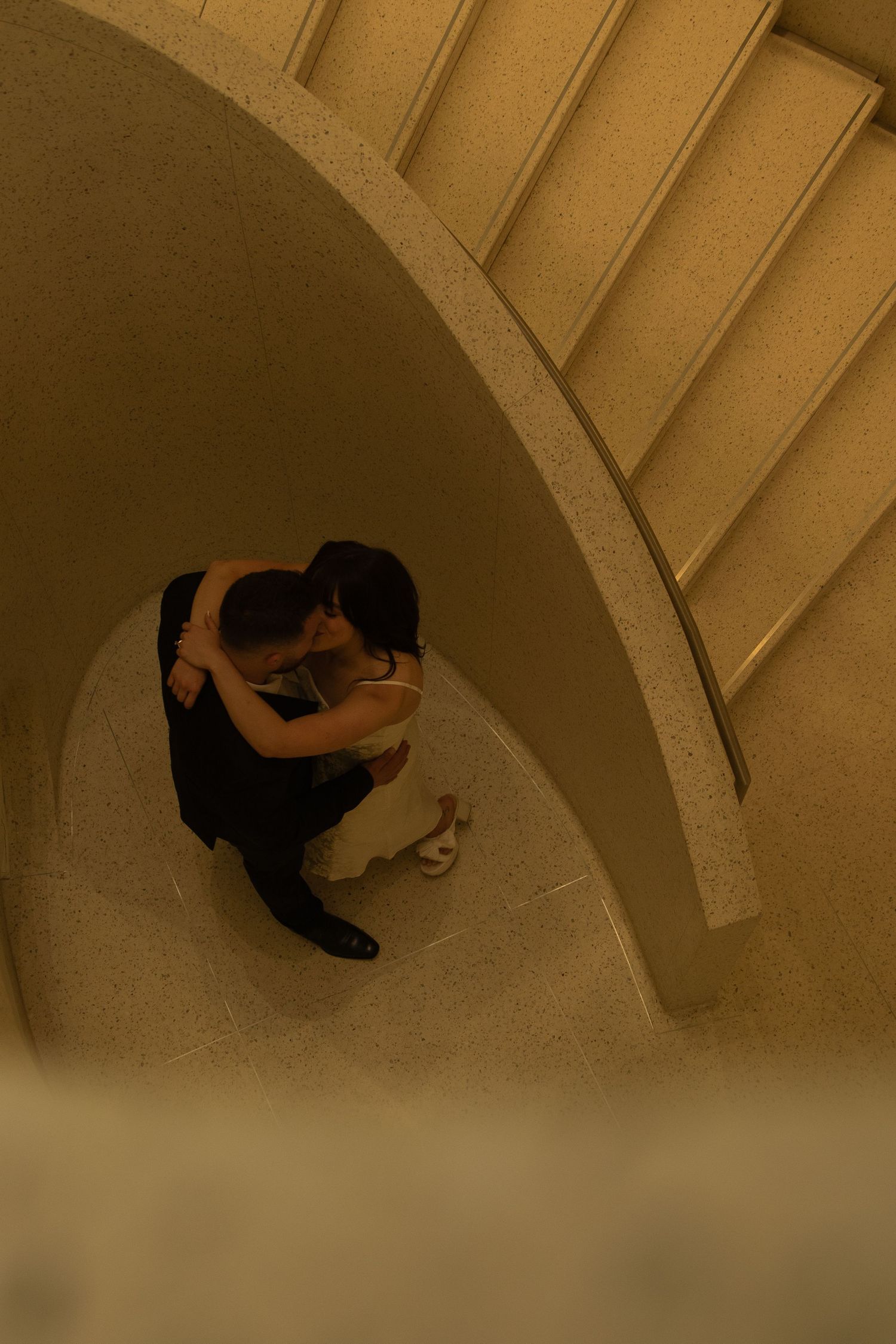 Overhead view of a couple dancing in an arched hallway.
