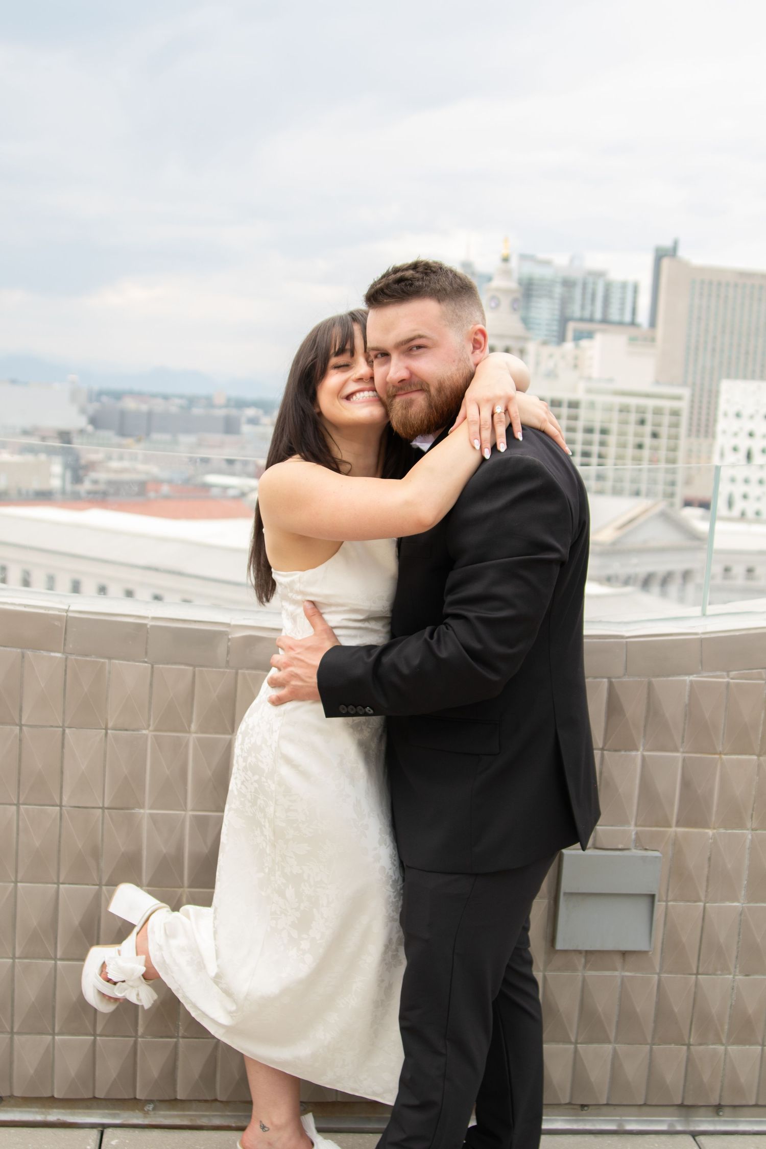 Romantic couple sharing intimate moments on a rooftop terrace with city skyline in the background.