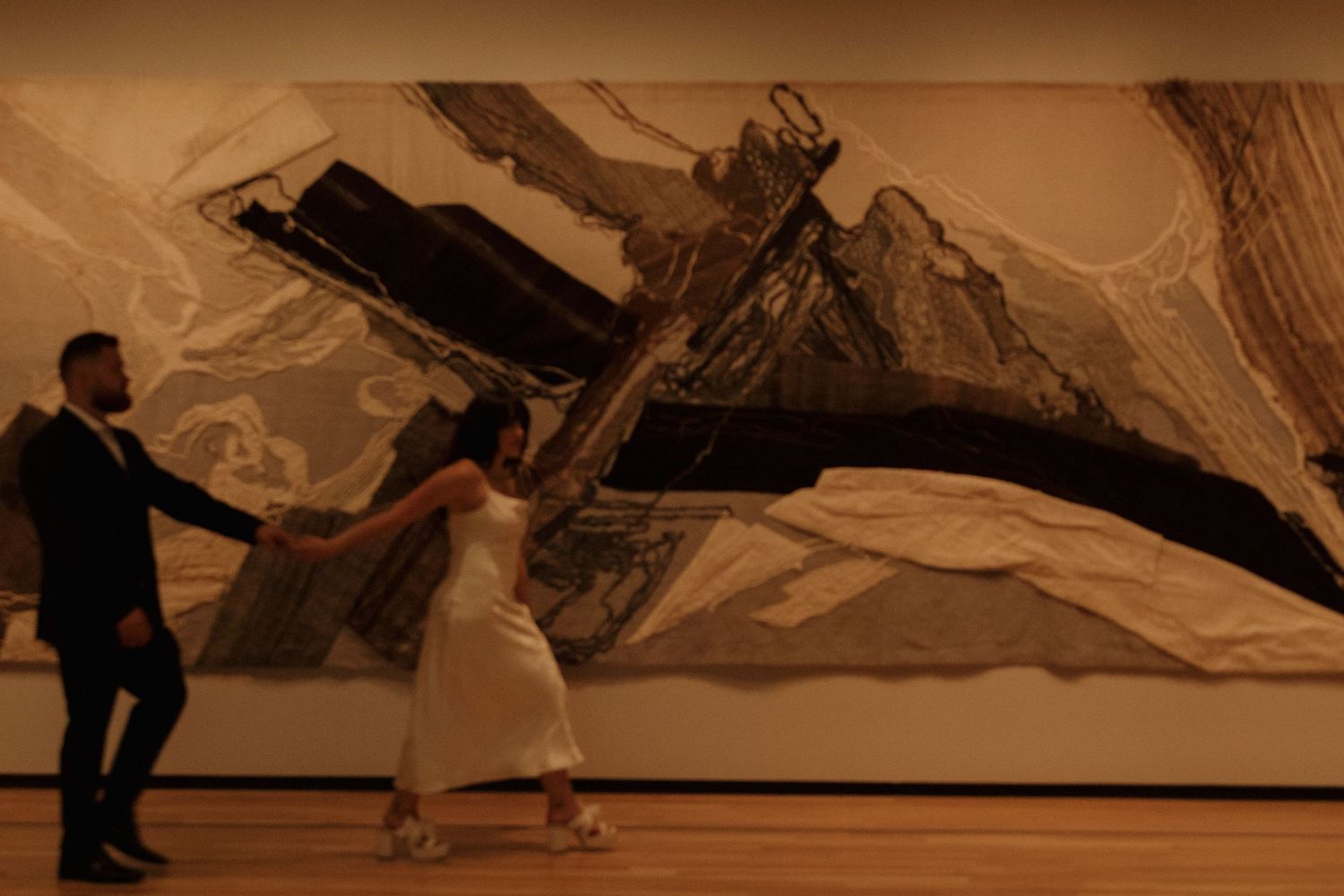People viewing large-scale abstract artwork stretching across museum wall.