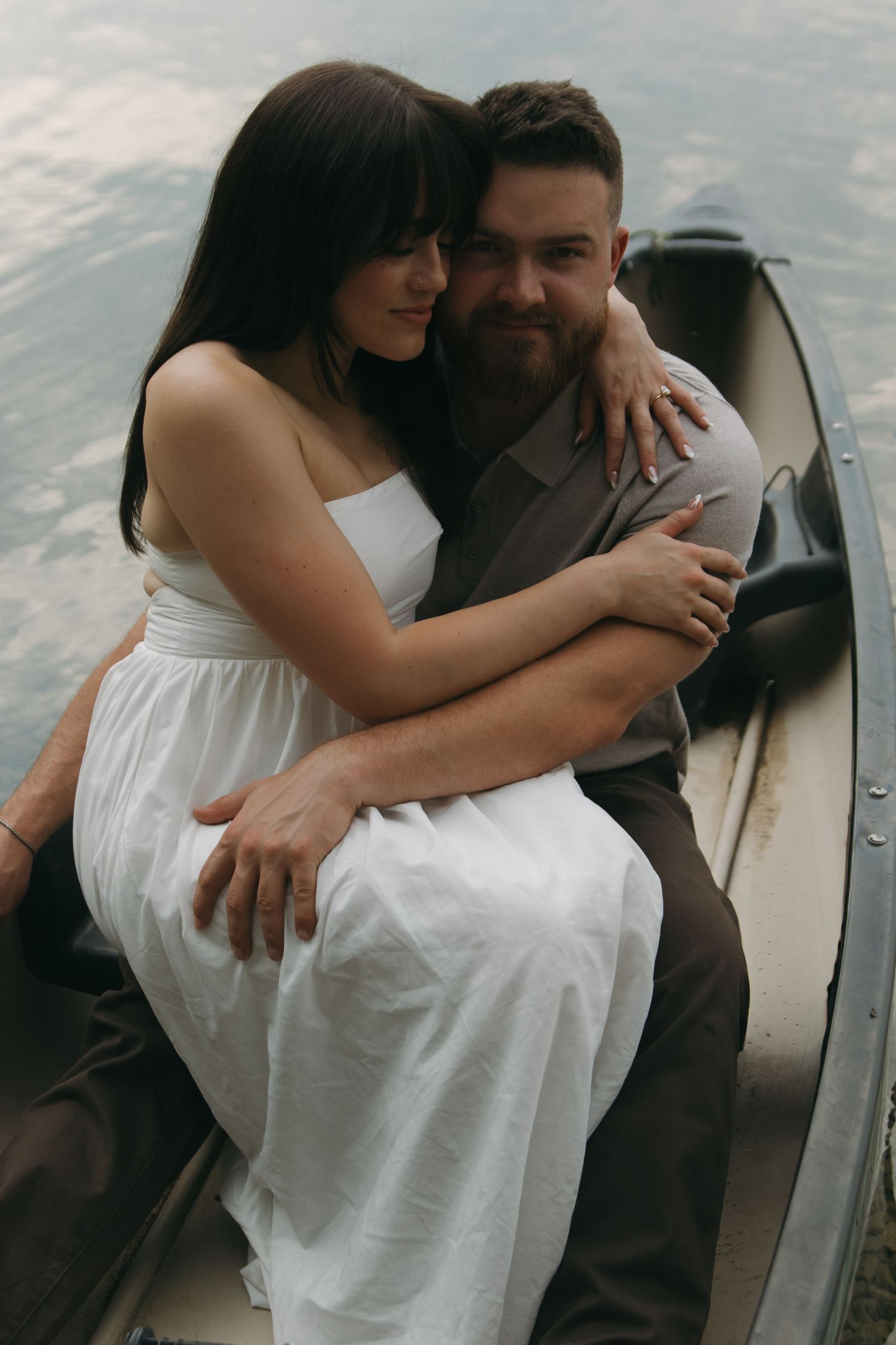 An intimate moment captured between two people in a canoe wearing white and gray.