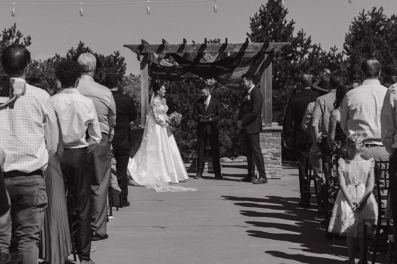 Black and white photo of wedding guests mingling at an outdoor ceremony.