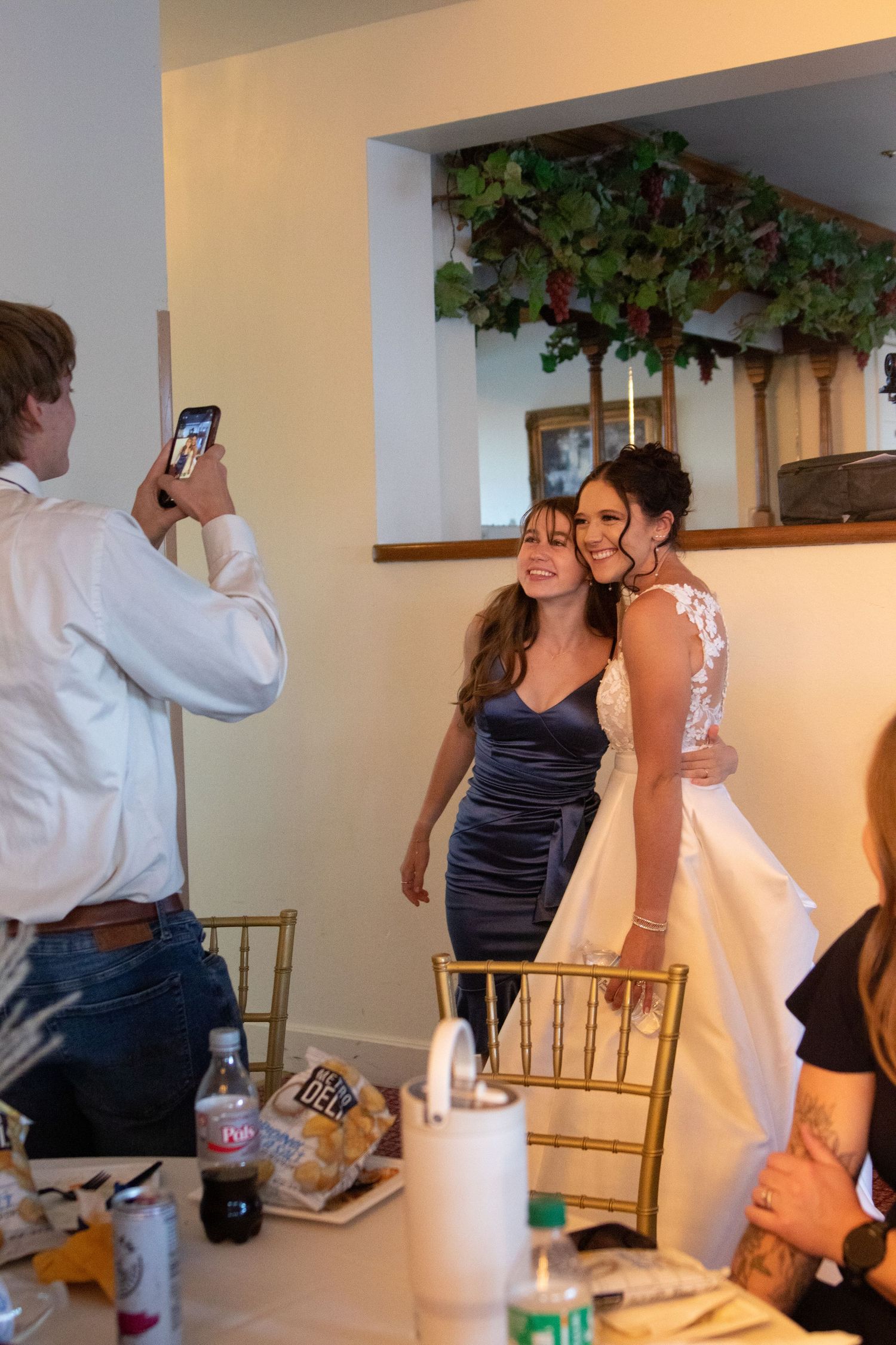 Wedding guests mingling and taking photos in an indoor reception space.