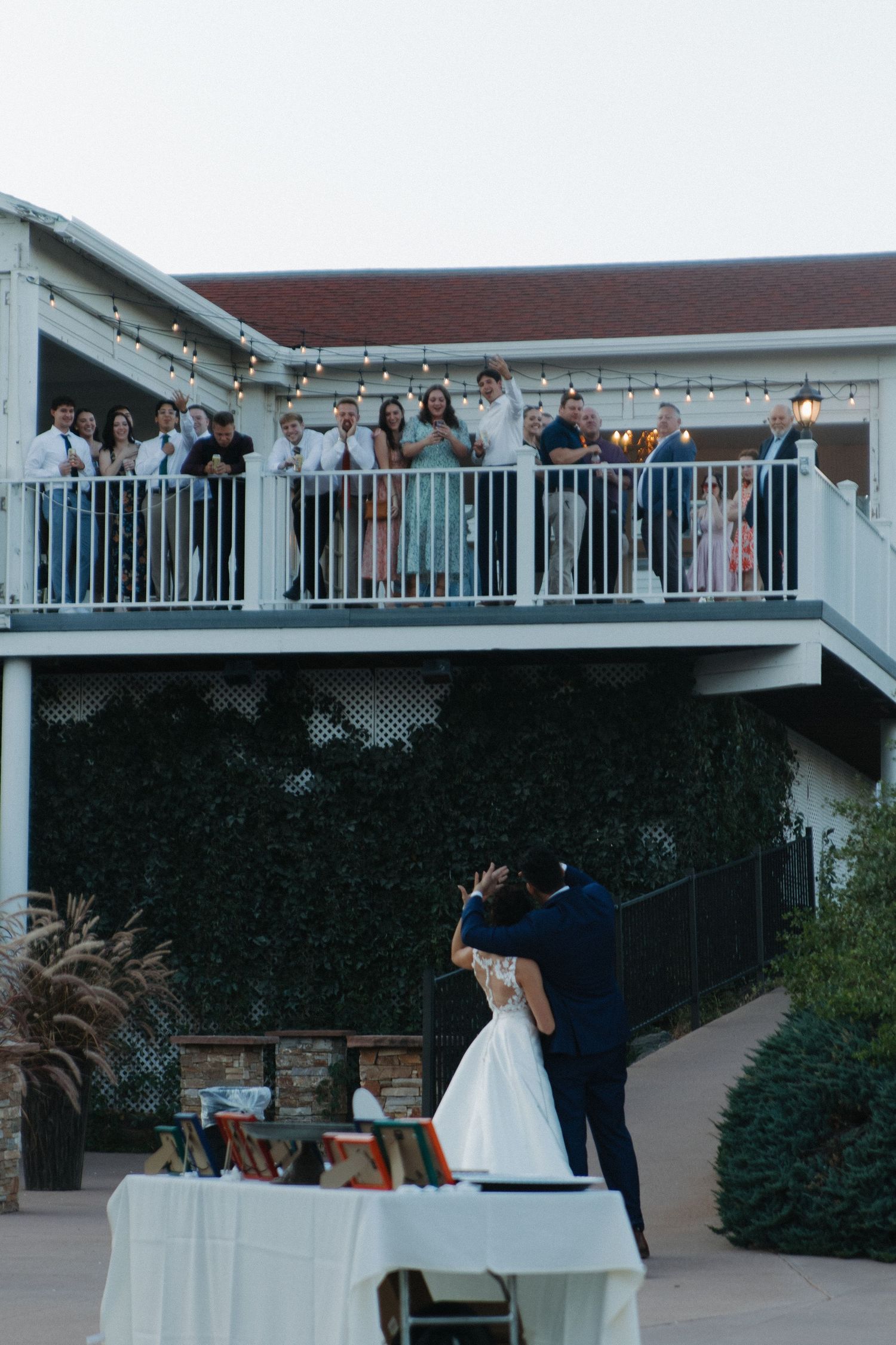 Wedding reception venue with guests gathered on white balcony at dusk.