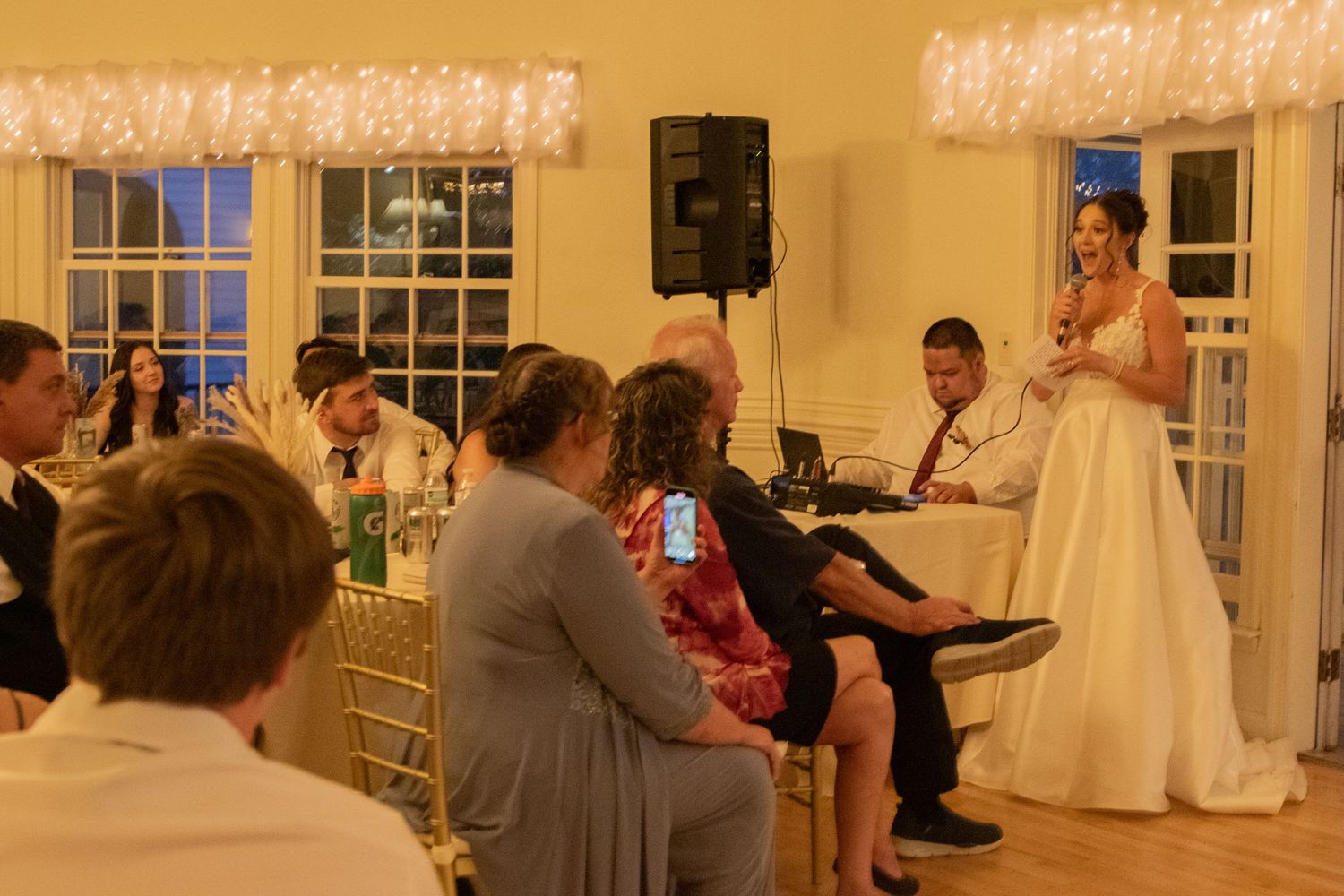 Wedding reception in warmly lit ballroom with traditional decor.