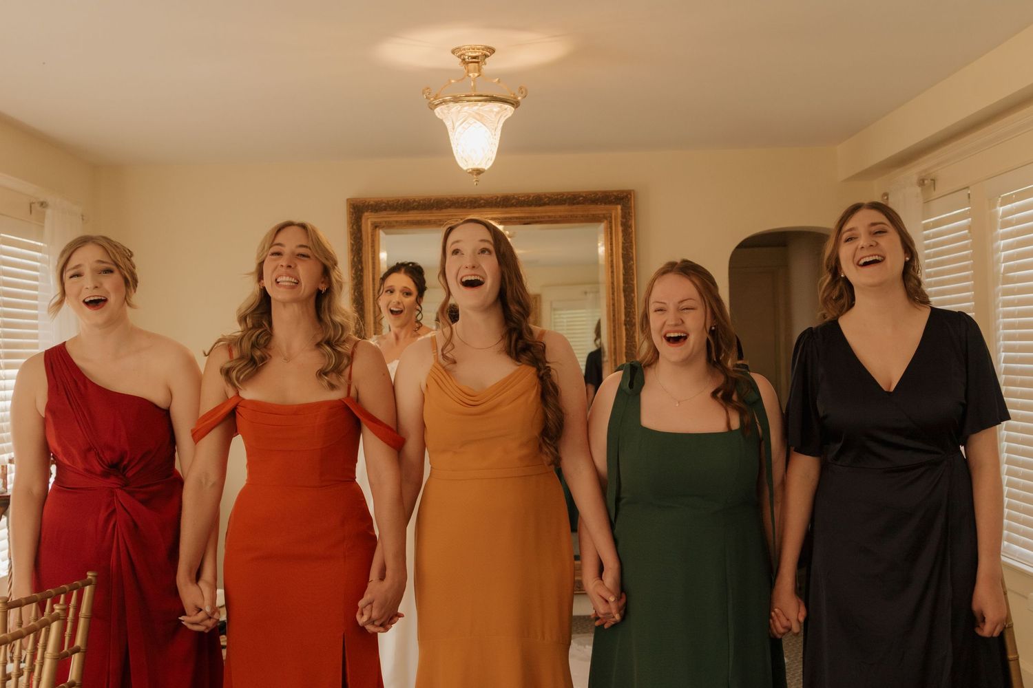 Wedding party members wearing jewel-toned dresses standing in a row.
