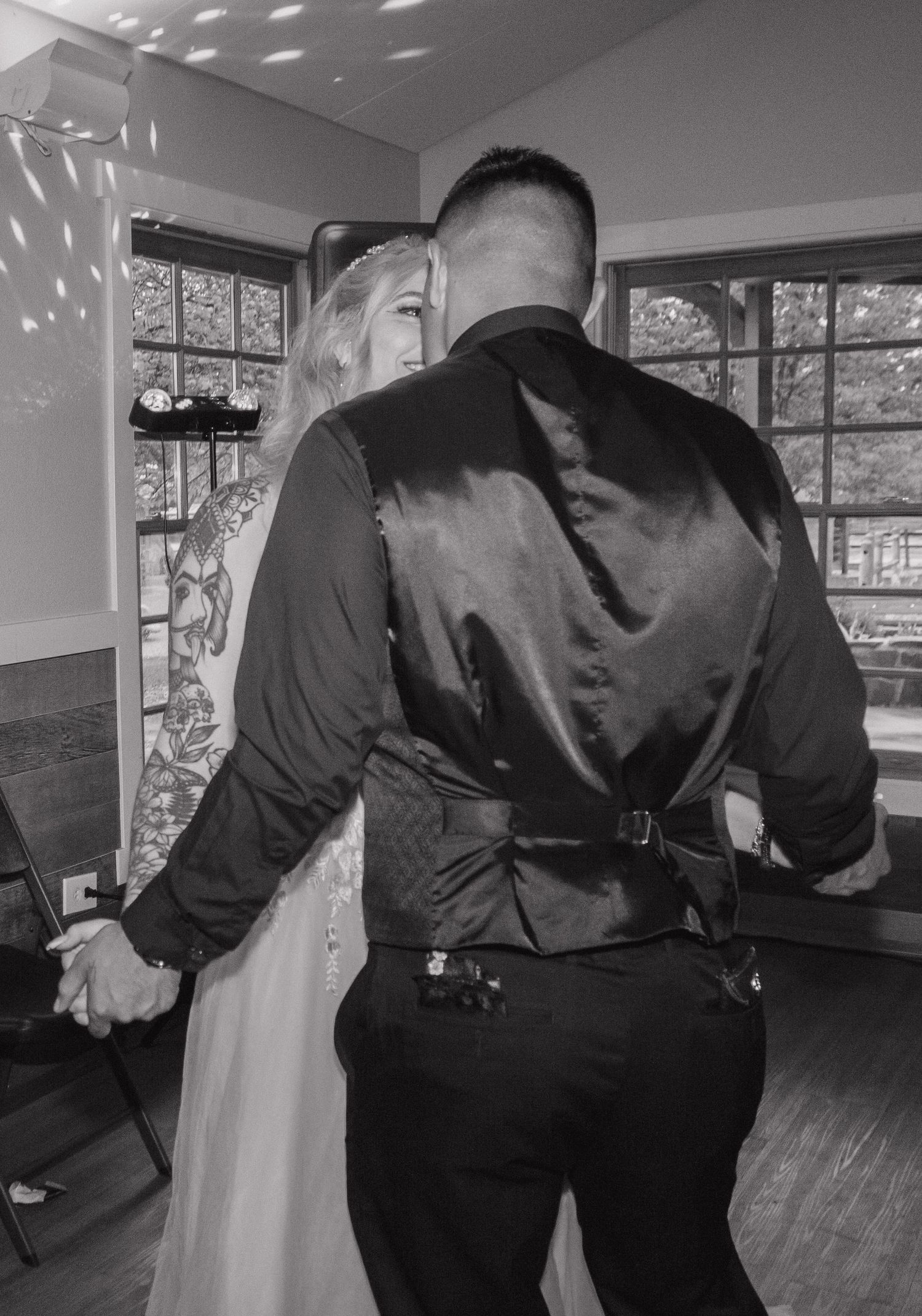 A couple in formal attire dances close together in black and white photography.