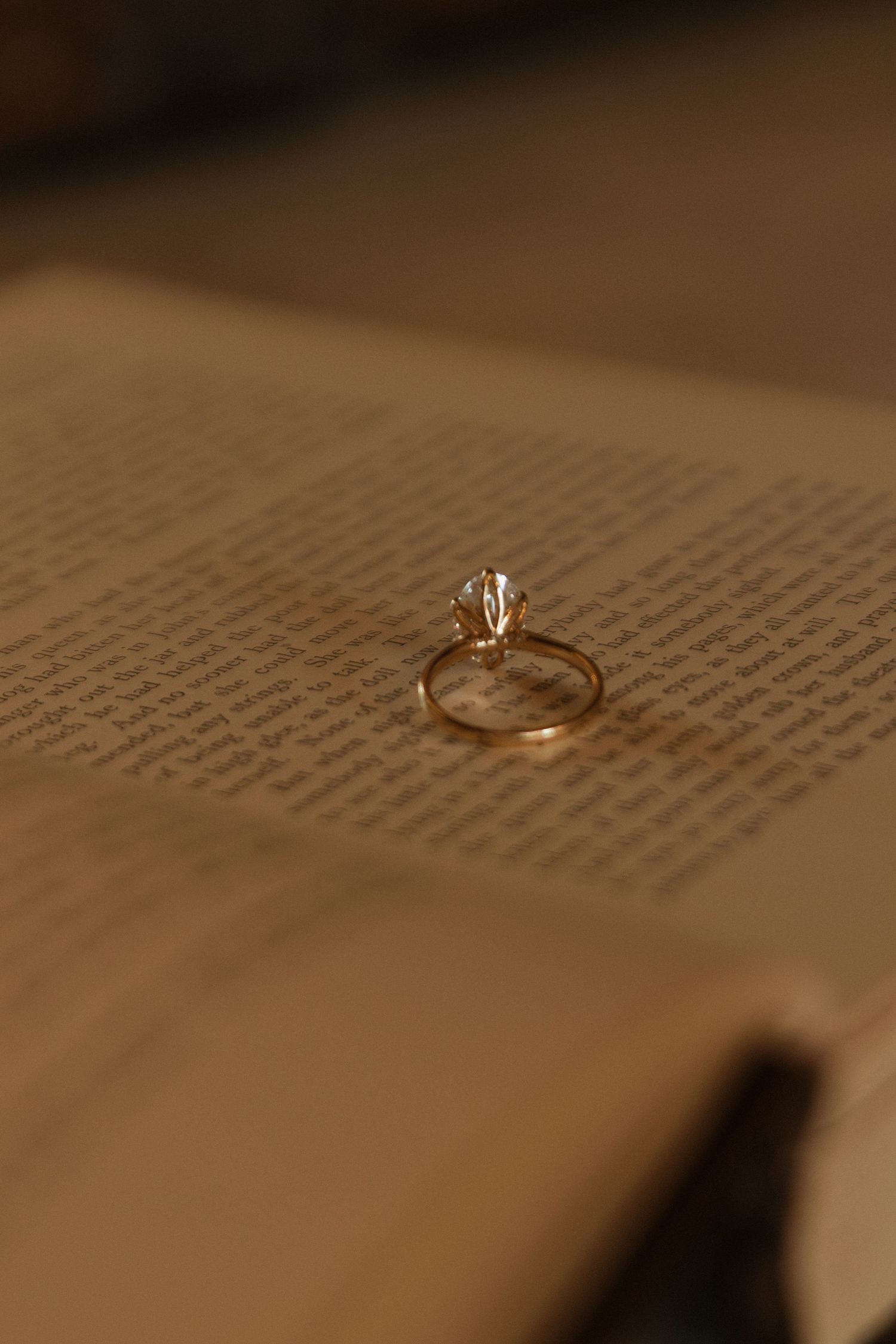 Wedding ring resting on pages of text with shallow depth of field.