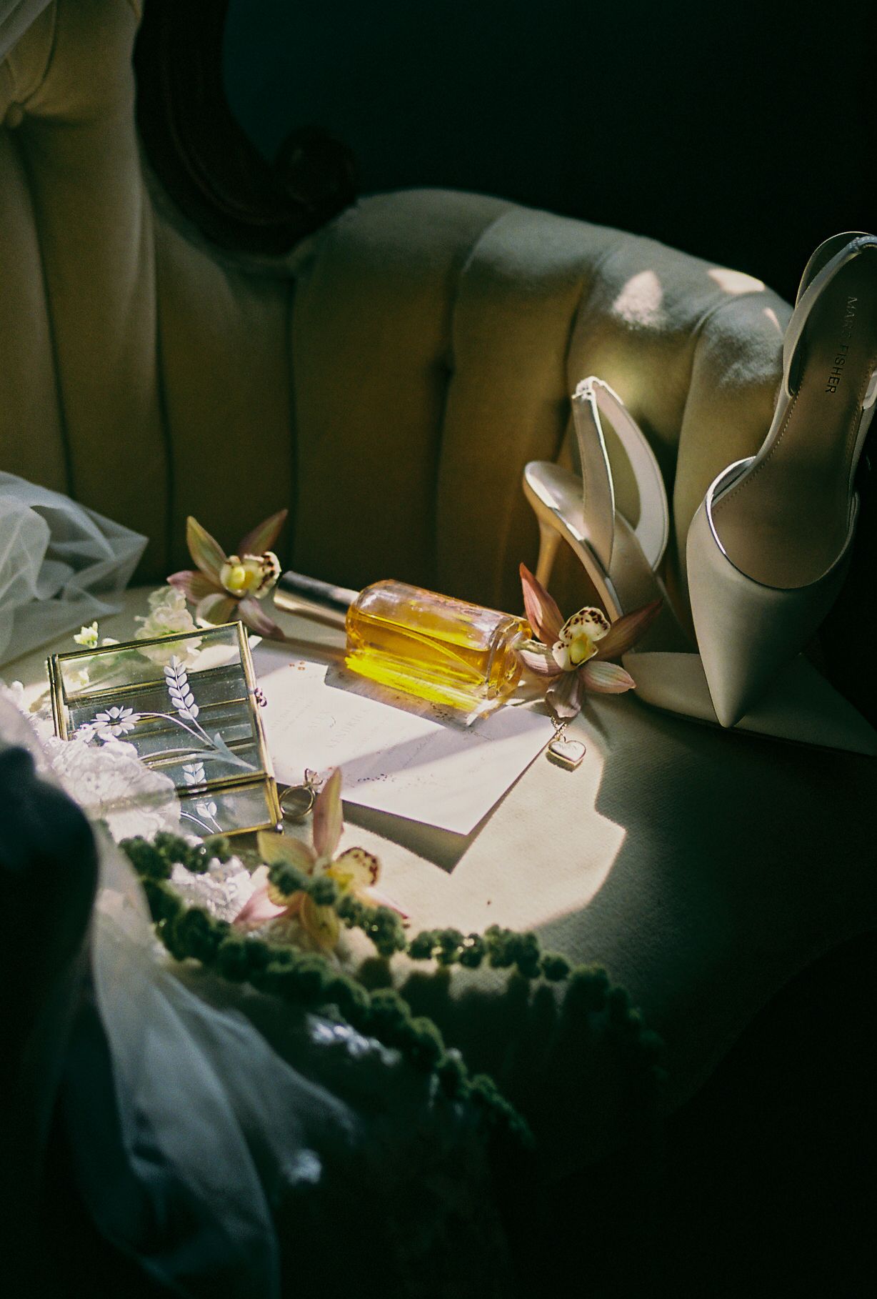 Wedding details photographed in moody lighting with perfume bottles and delicate decorations.